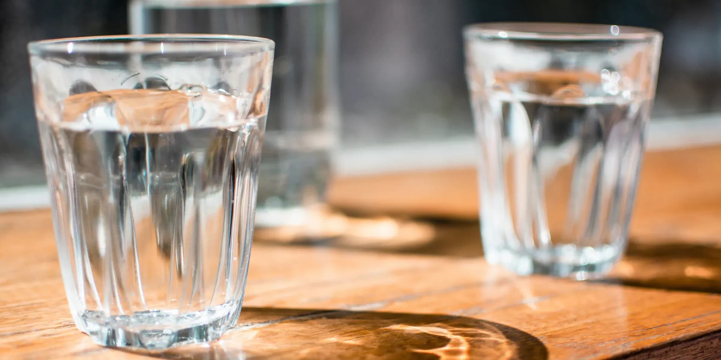 Zwei Wassergläser stehen auf einem Holztisch