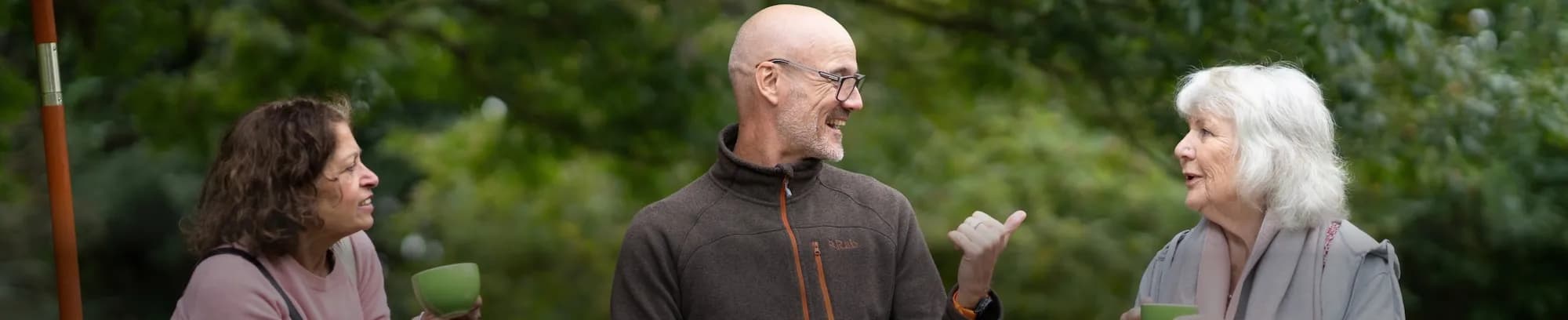Älterer Herr mit Brille unterhält sich mit zwei Frauen während einer Fastenkur
