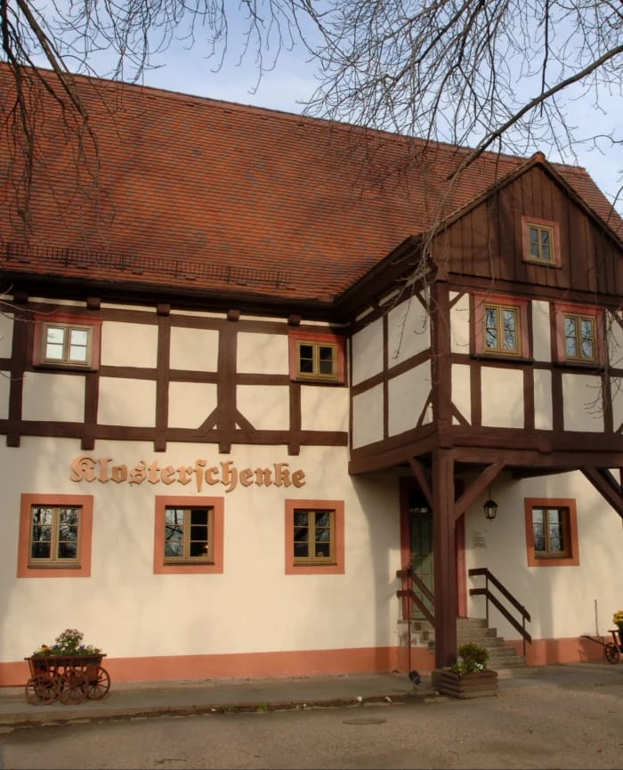 Fachwerkhaus der Klosterschenke mit rotem Ziegeldach, Holzbalkon und Schriftzug an der Wand