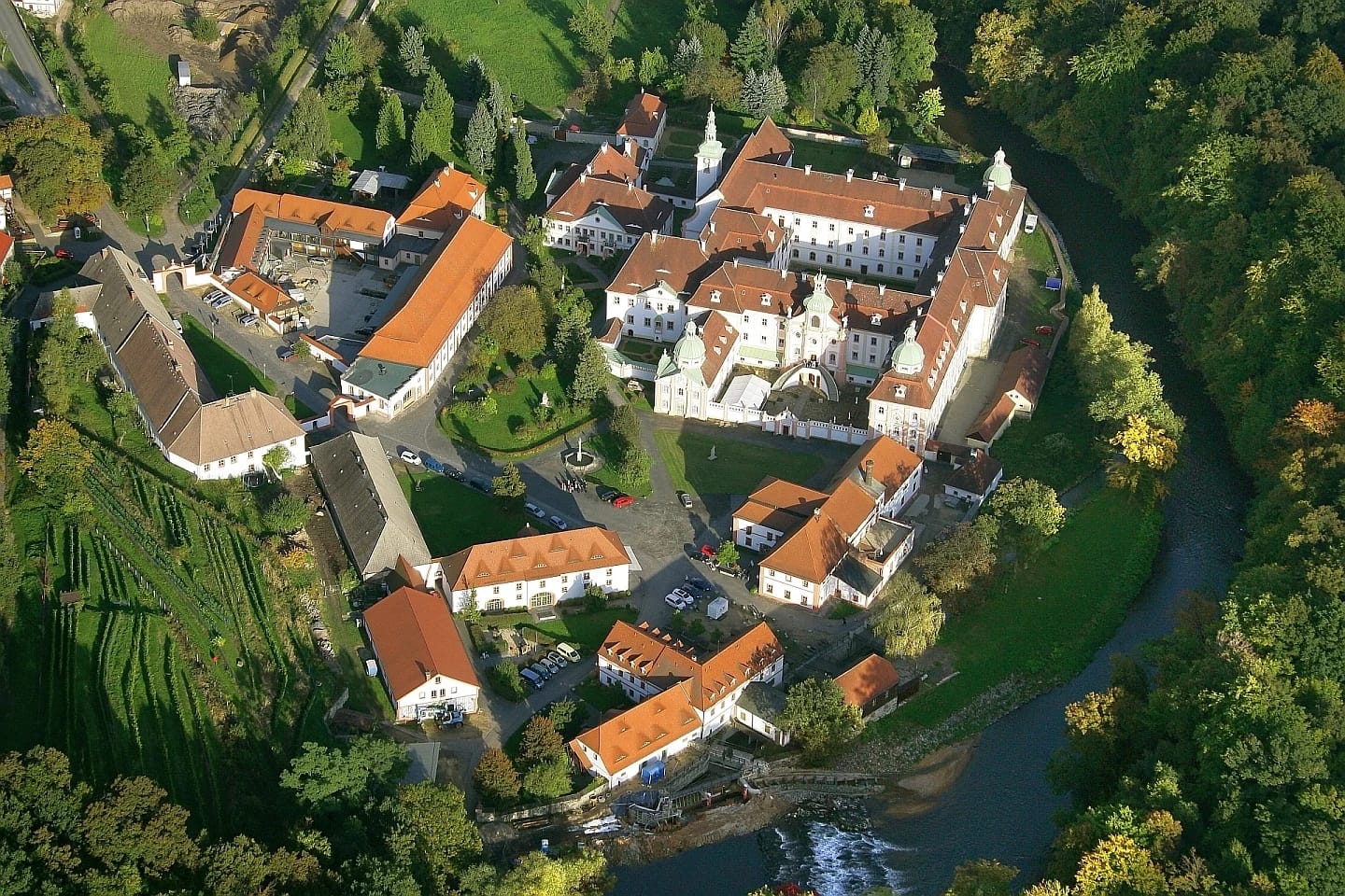 Luftaufnahme der Klosteranlage mit roten Ziegeldächern, Weinberg und Flussschleife