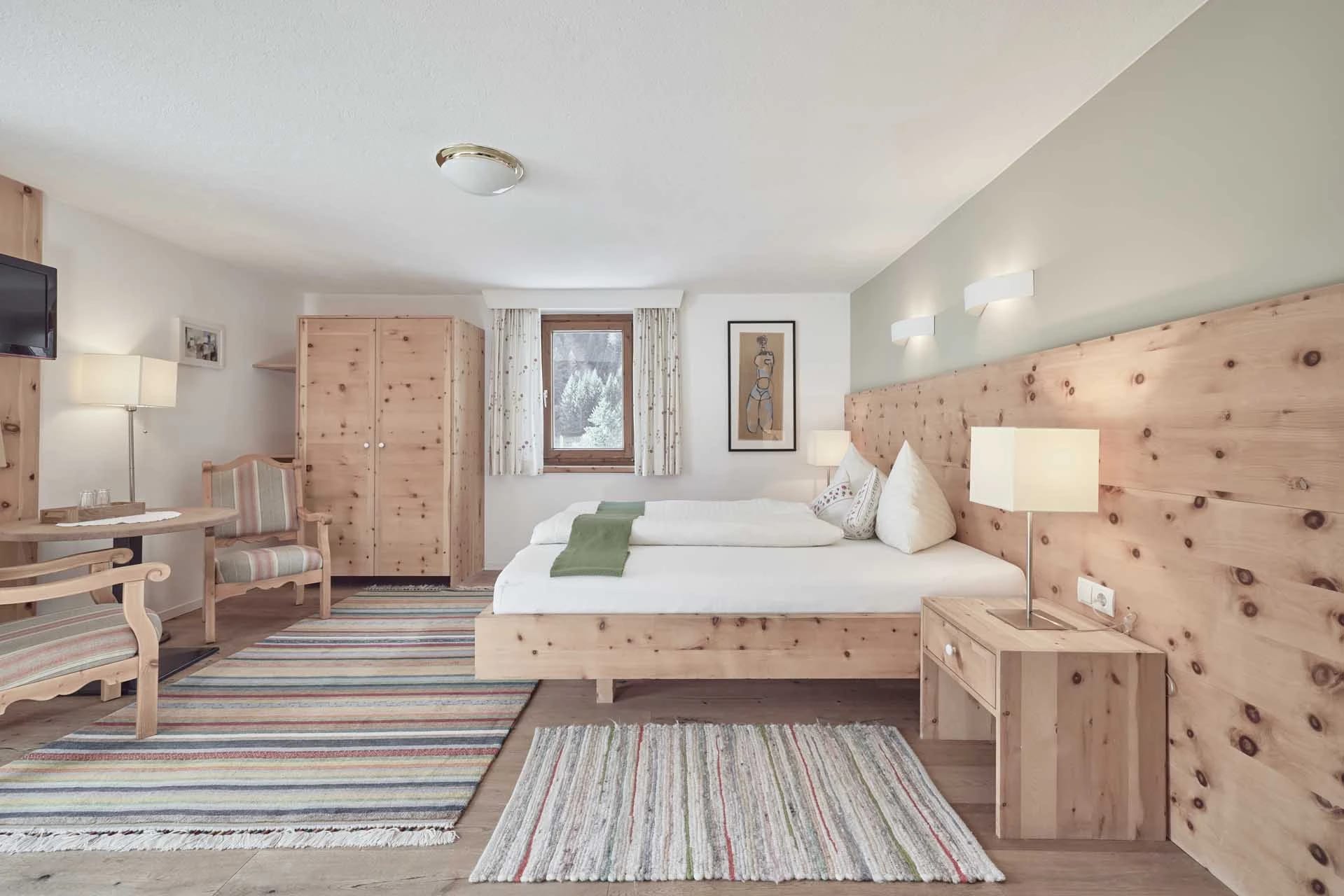 Doppelzimmer in Zirbenholz mit Doppelbett und Fenster mit Bergblick