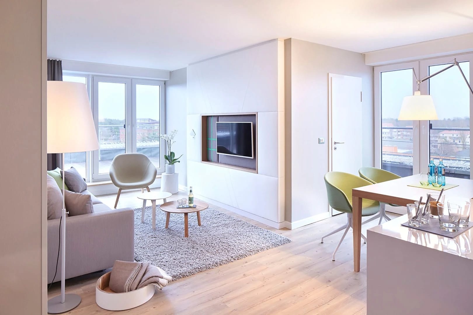 Wohnbereich einer Suite mit Sofa, Sesseln, Esstisch und großen Fenstern