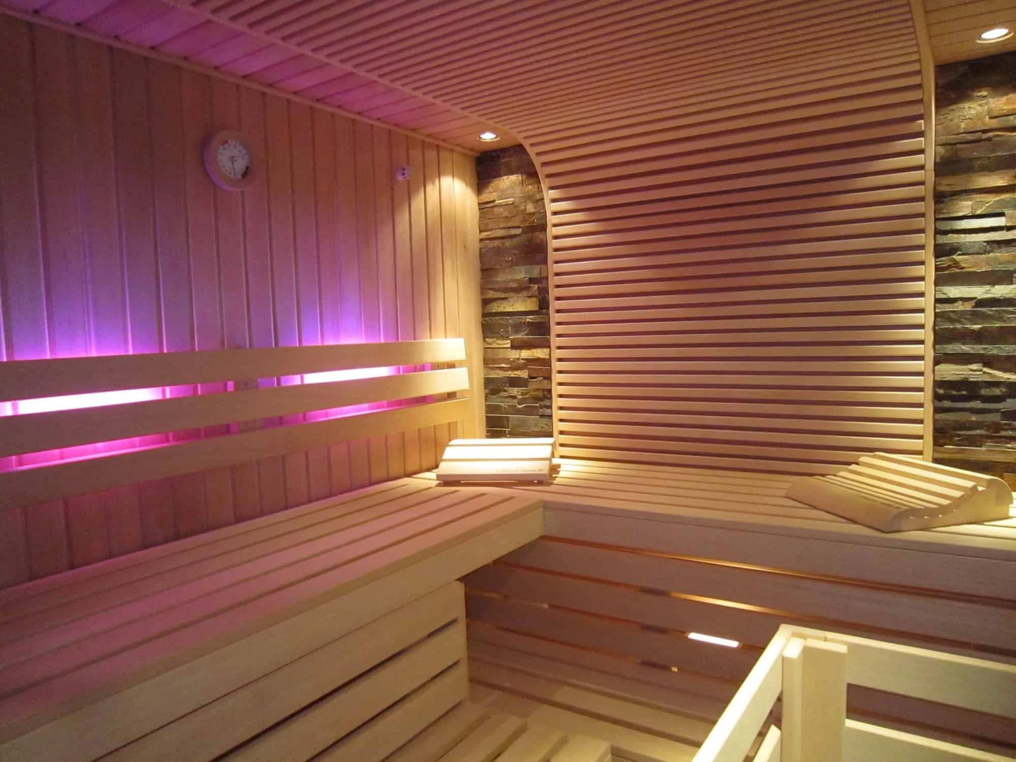 Sauna mit Holzbänken und farbiger Beleuchtung