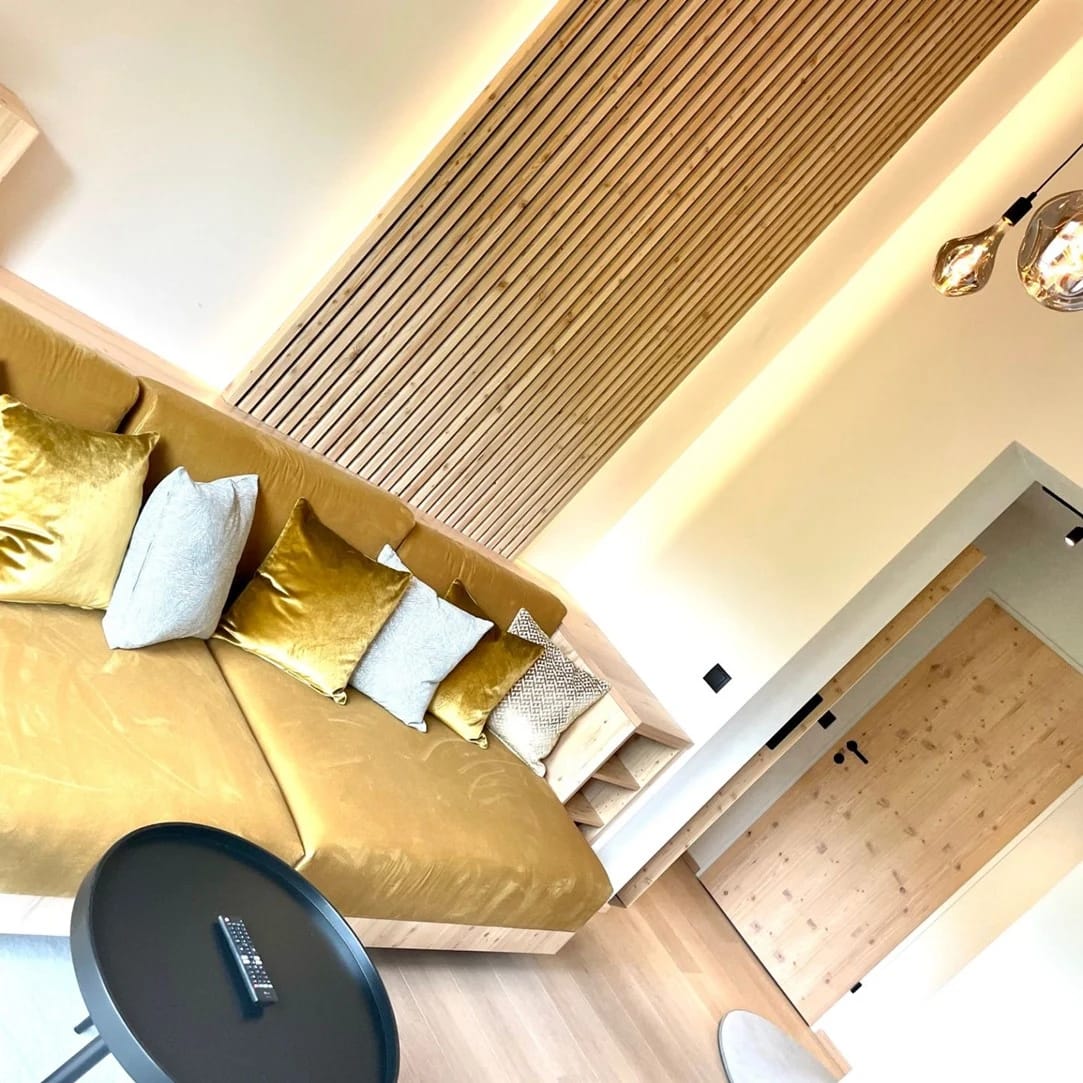 Loungebereich mit goldfarbenem Sofa und Holzverkleidung