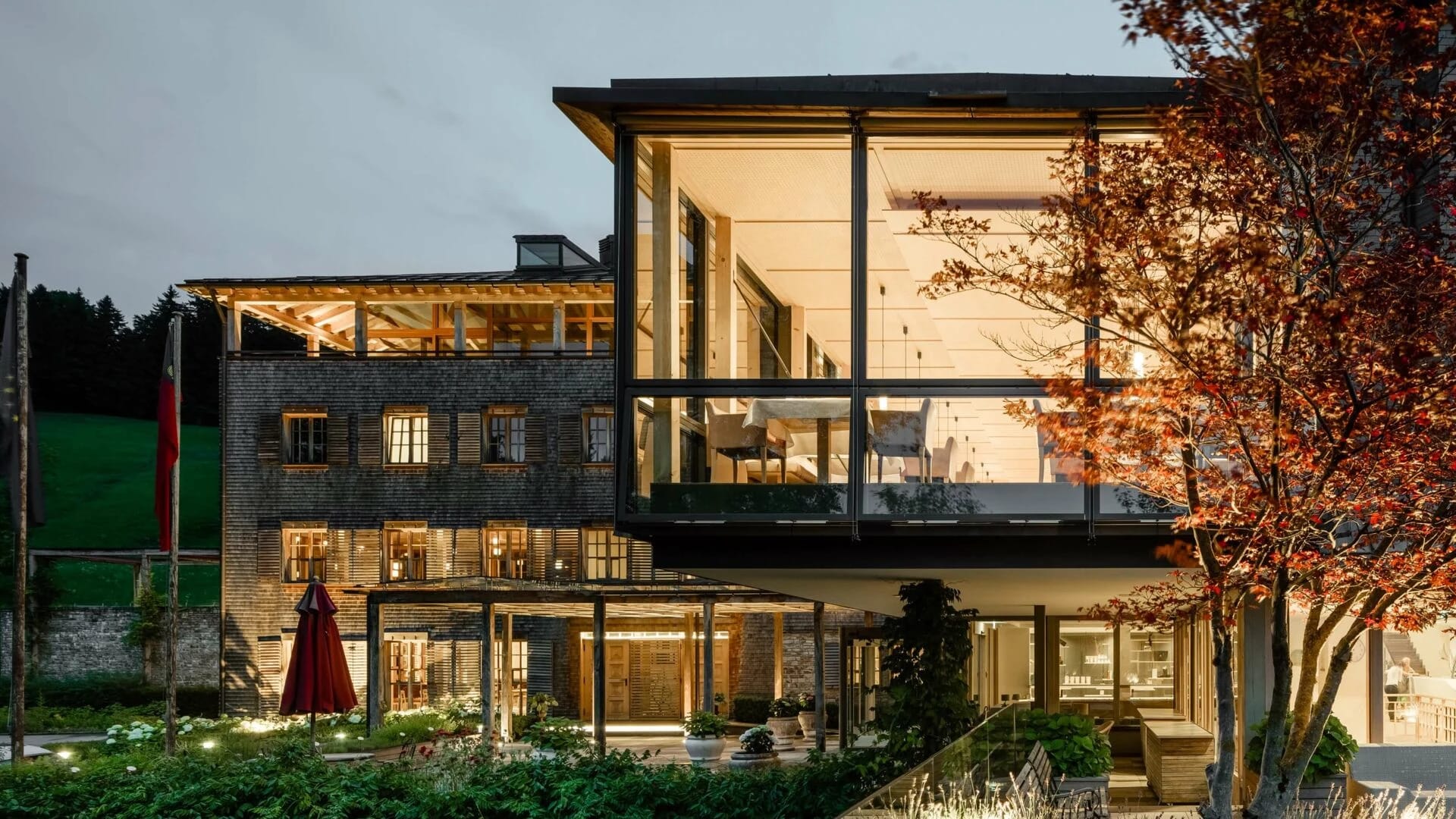 Beleuchtete Hausfront mit Glasfassade und Terrassen in der Abenddämmerung