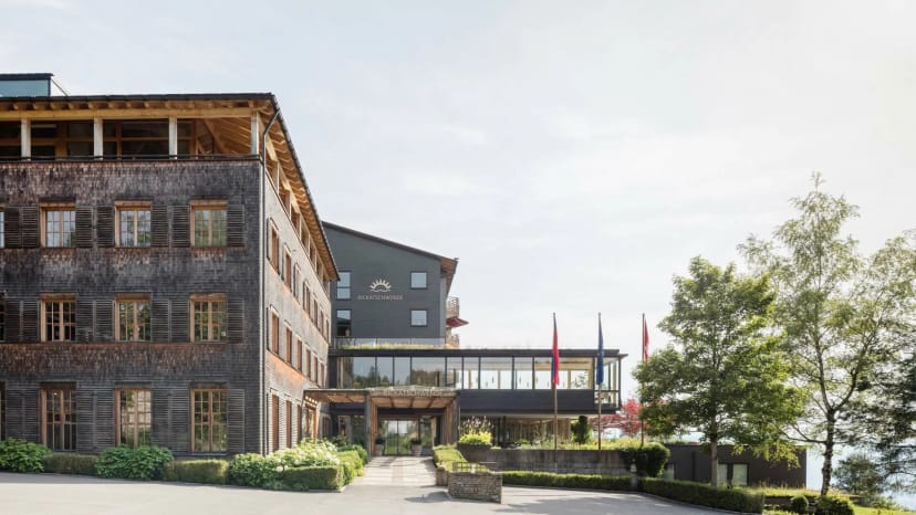 Außenansicht des Hauses mit Schindelfassade, Holzobergeschoss, Eingangsbereich und Fahnen