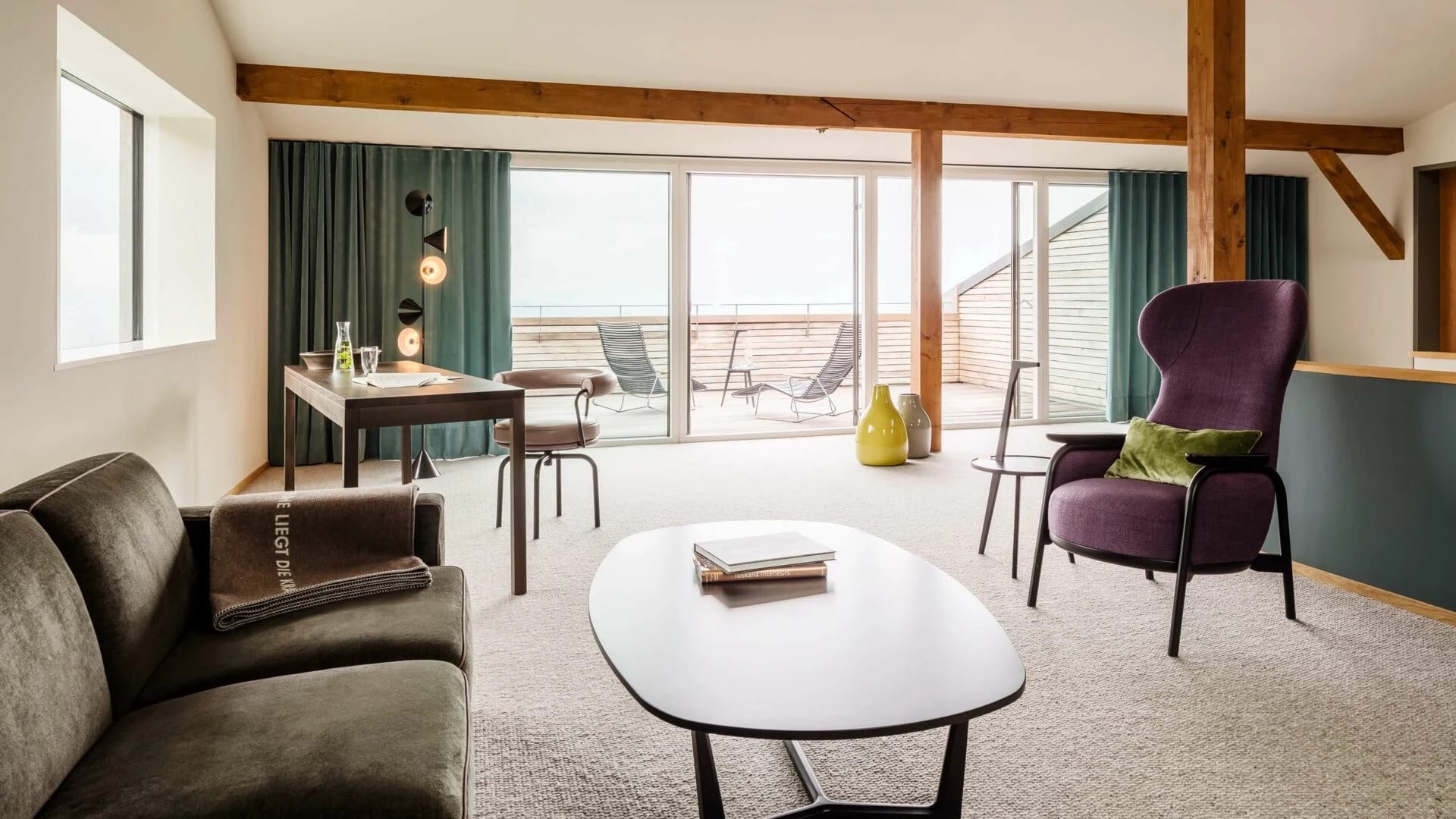 Suite mit Sofa, Sessel und Esstisch, dahinter Balkon mit Liegestühlen