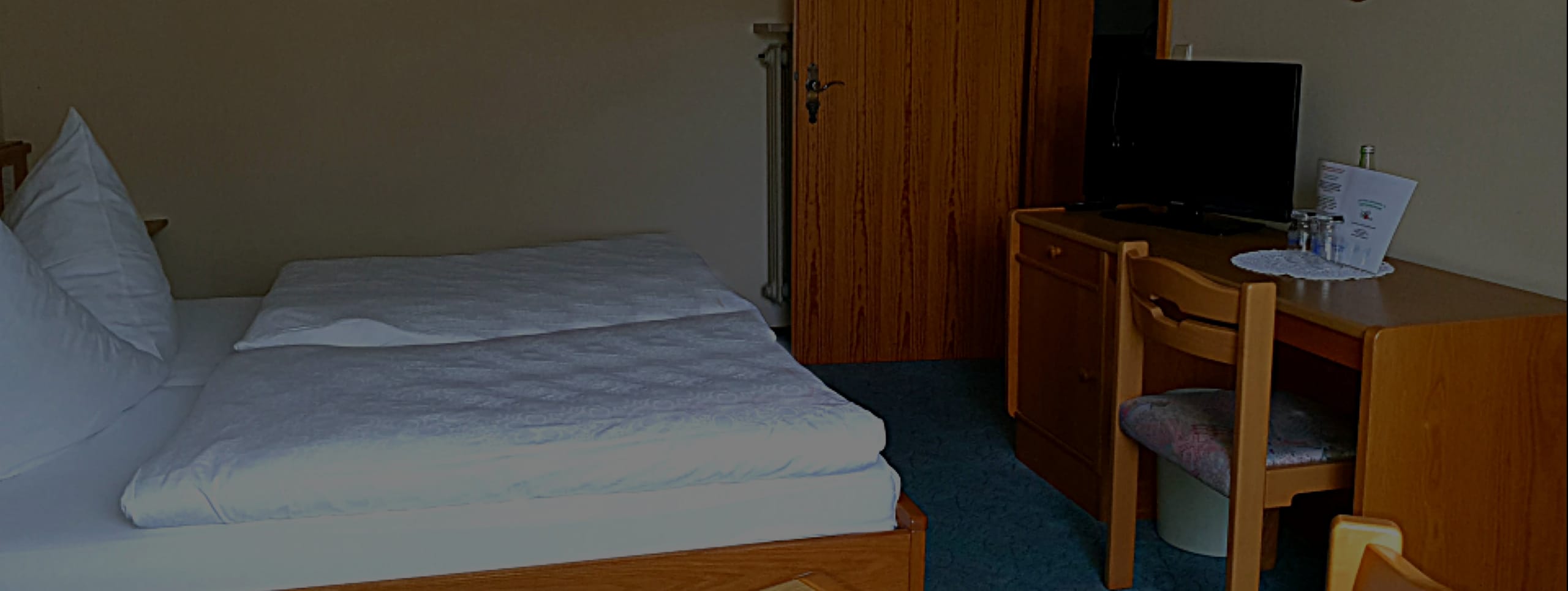 Gästezimmer mit Doppelbett, Schreibtisch und Fernseher