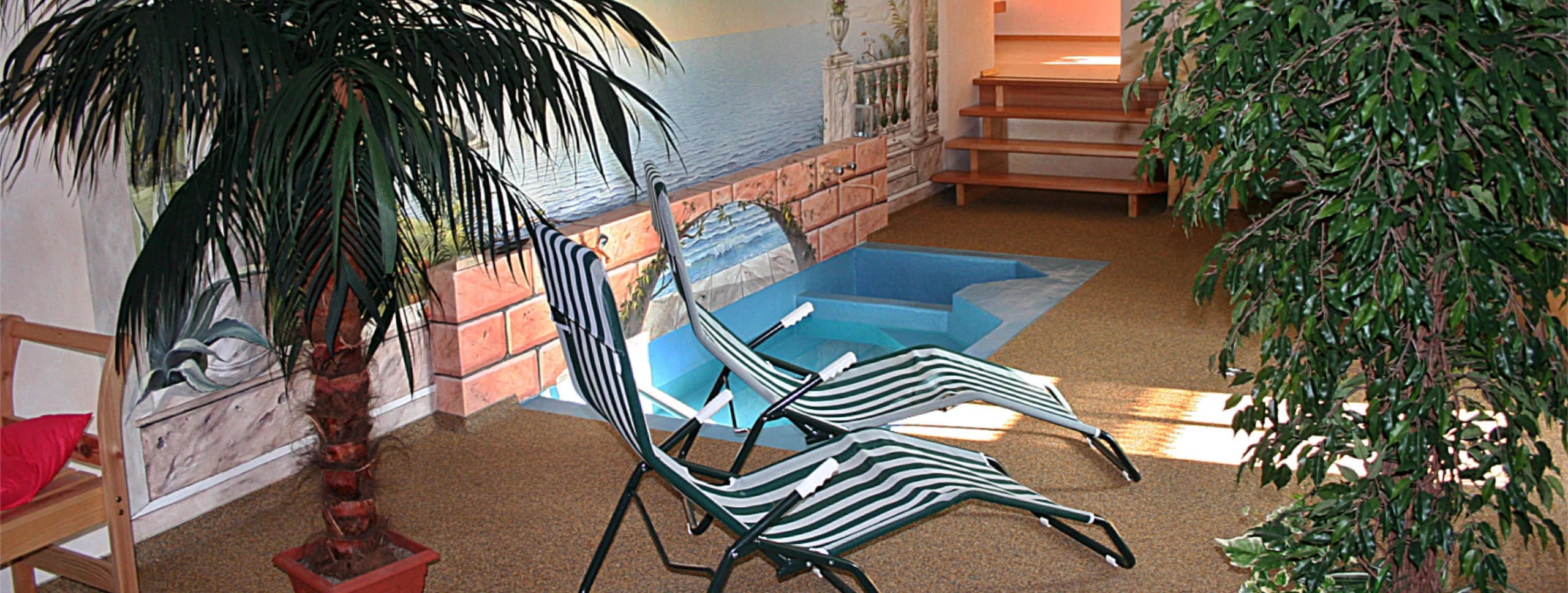 Wellnessbereich mit Relaxliegen, Palme und kleinem Tauchbecken