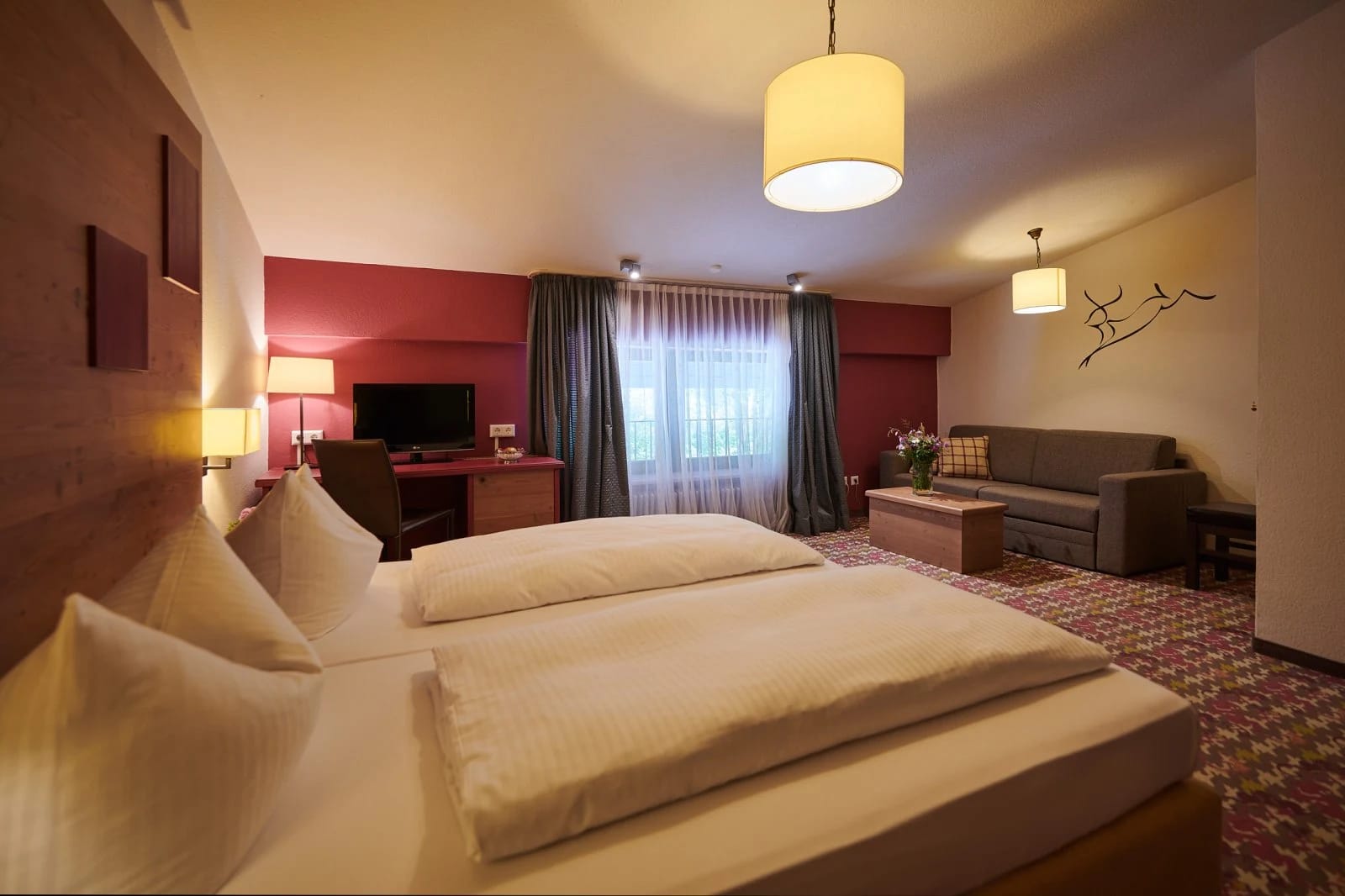 Doppelzimmer mit Doppelbett, Sofa und roter Wand
