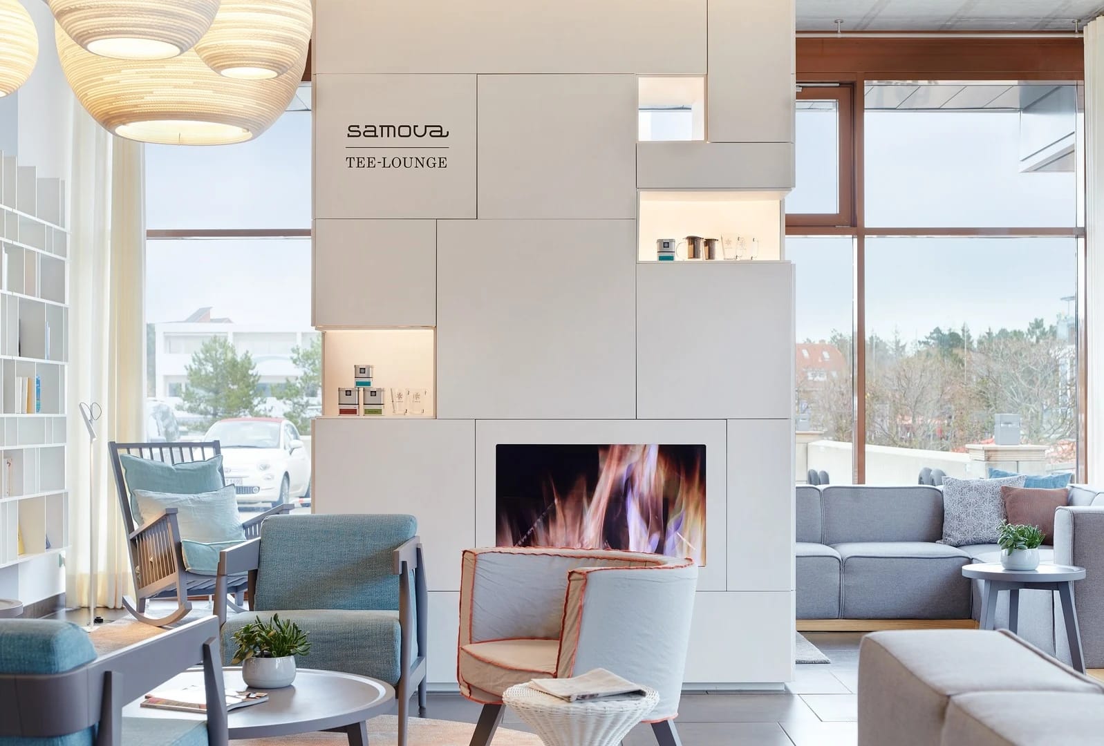 Lounge mit offenem Kamin, Sesseln und Sofas neben bodentiefen Fenstern
