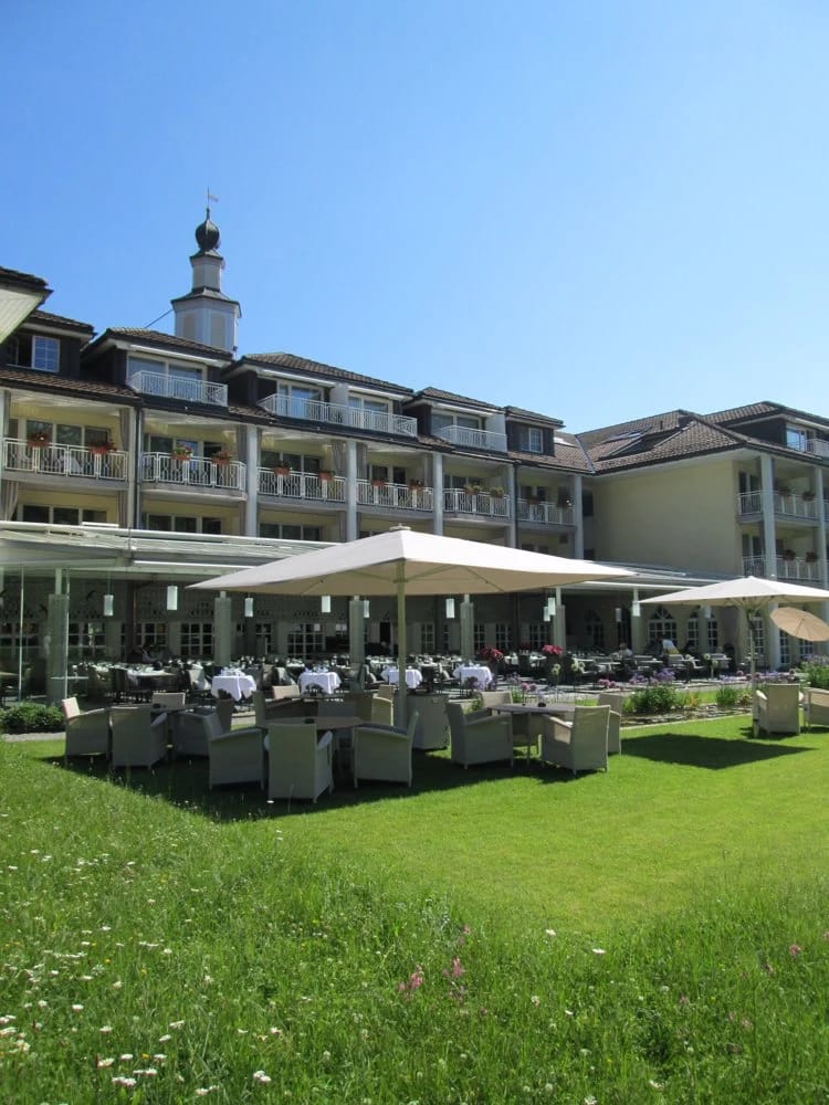Terrasse und Außenbereich mit Liegestühlen und Sonnenschirmen, Hauptgebäude im Hintergrund