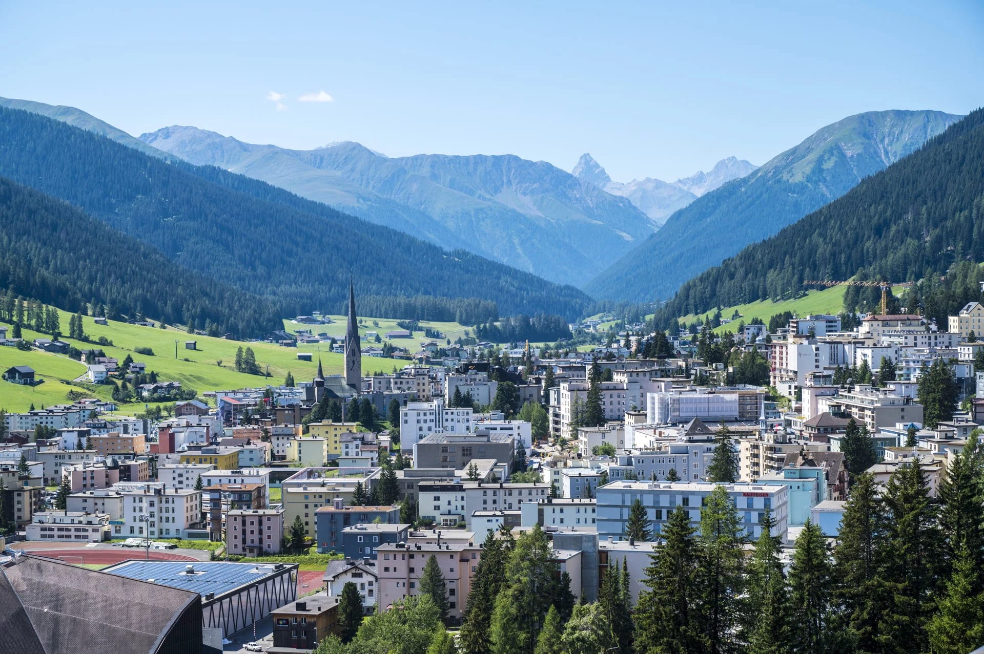 Blick über Davos ins Bergtal mit bewaldeten Hängen im Sommer
