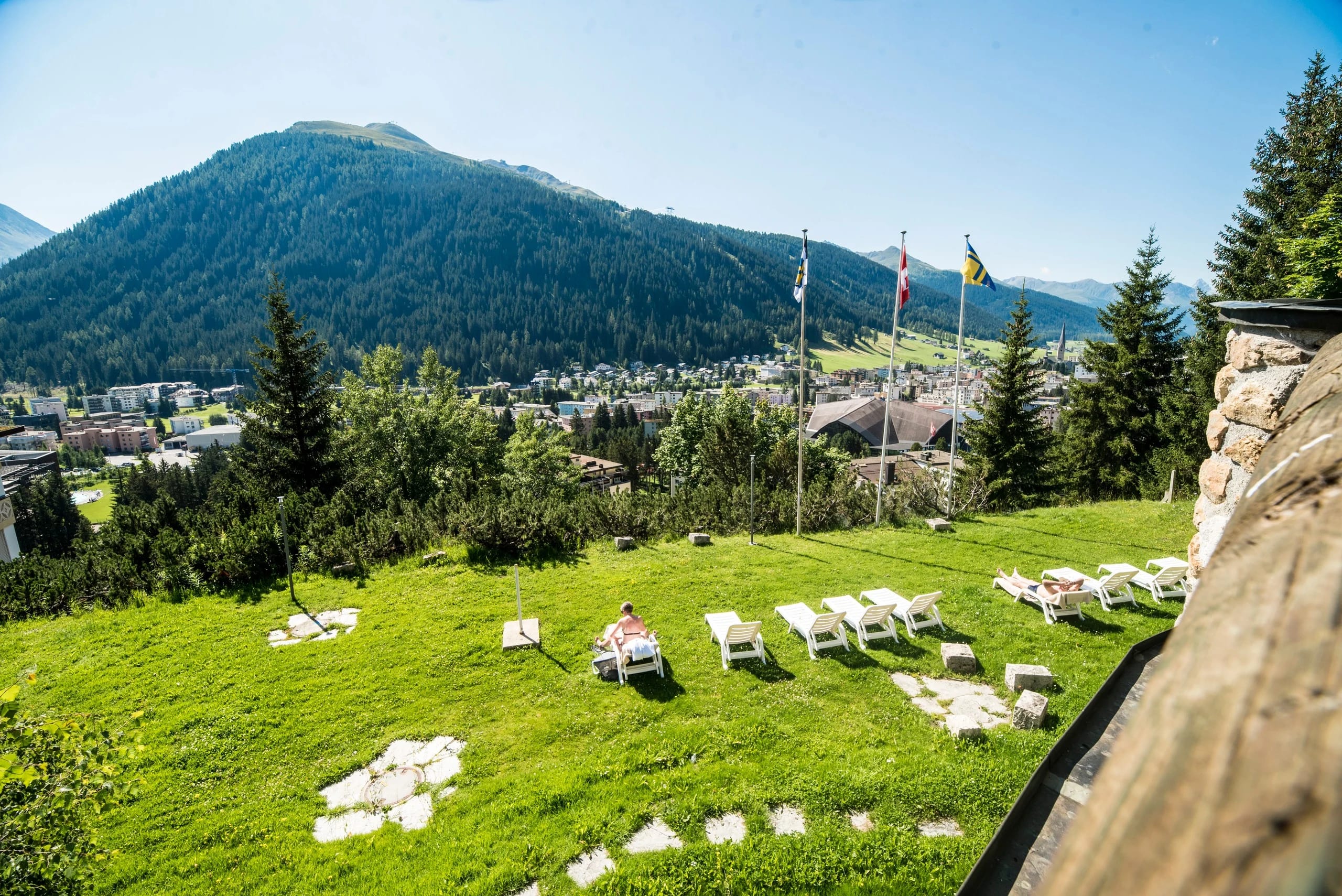 Liegewiese mit weißen Sonnenliegen oberhalb von Davos mit Blick auf die Berge