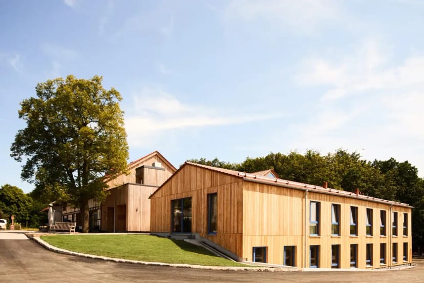 Gästehaus mit heller Holzfassade und Zufahrt bei blauem Himmel