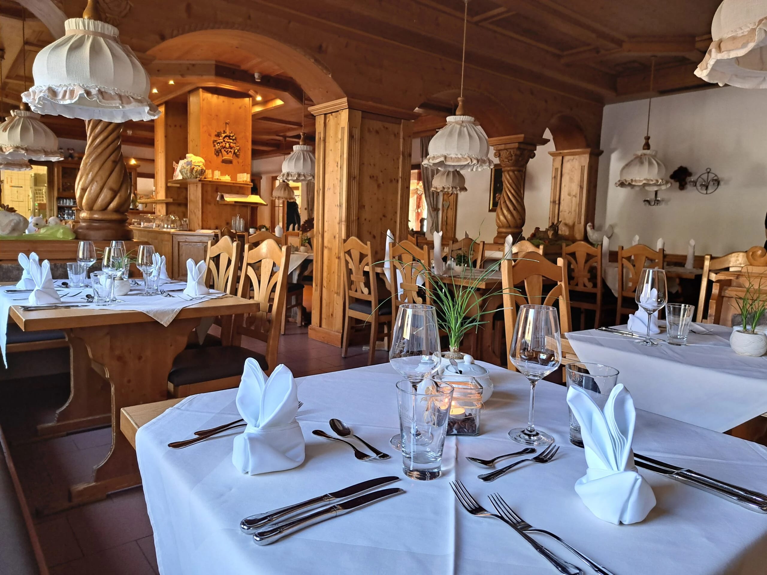 Restaurant mit holzvertäfelten Wänden, eingedeckten Tischen und Hängeleuchten