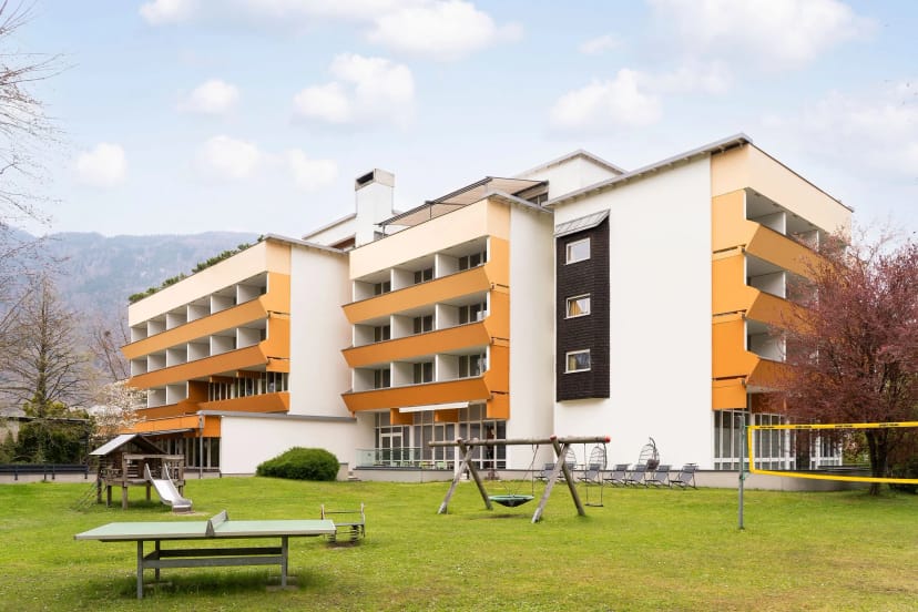 Außenansicht des Hotelgebäudes mit Liegewiese und Bergen im Hintergrund
