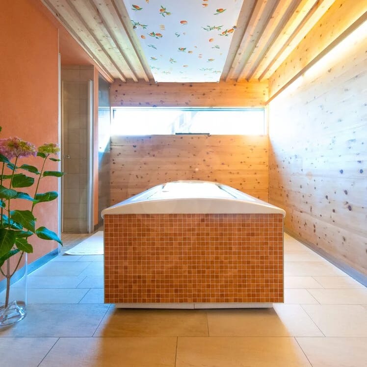 Spa-Raum mit gefliester Liege, Mosaikverkleidung und bunt gestalteter Decke