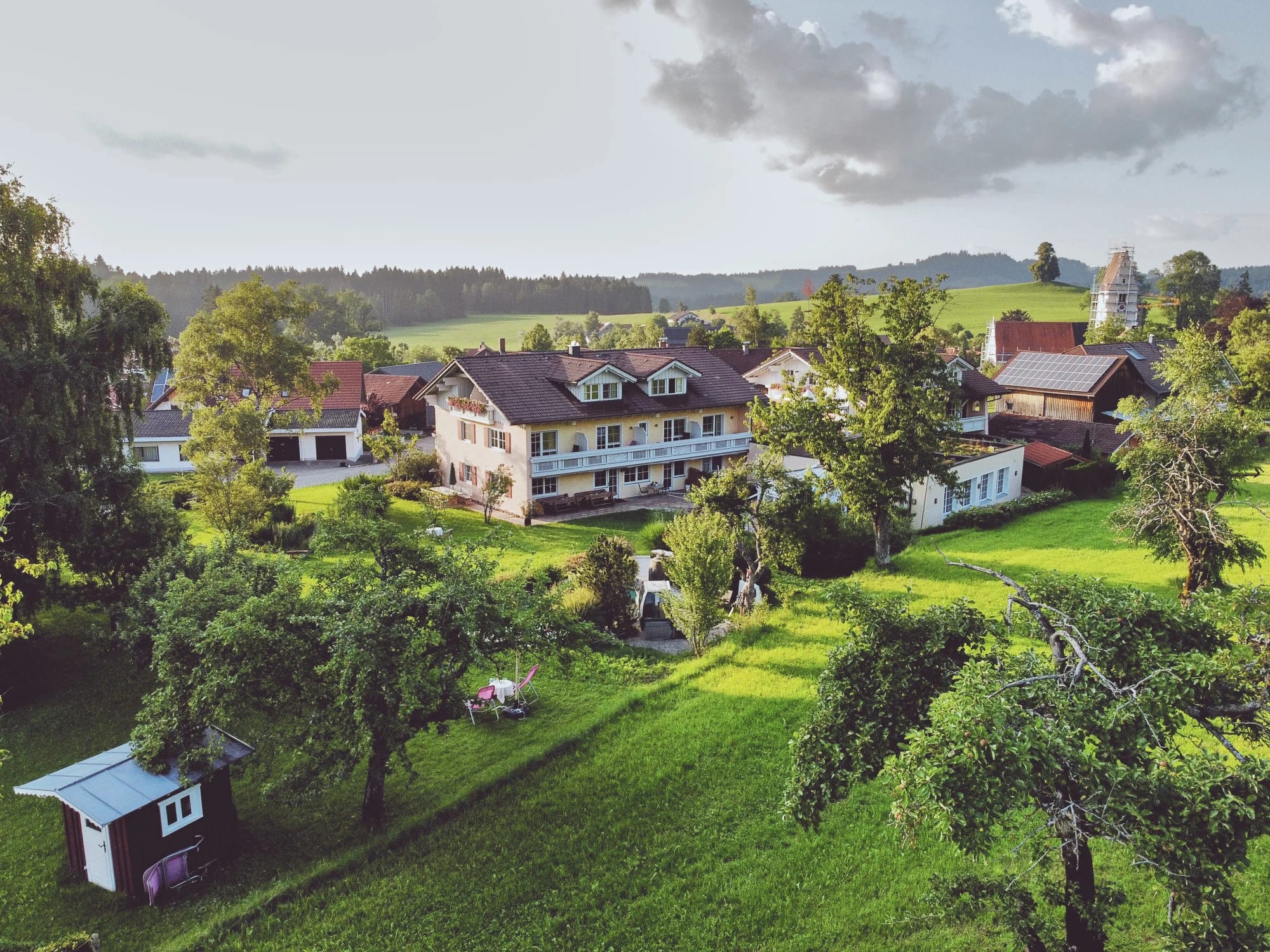 Luftaufnahme des Hauses zwischen Wiesen, Obstbäumen und Hügeln