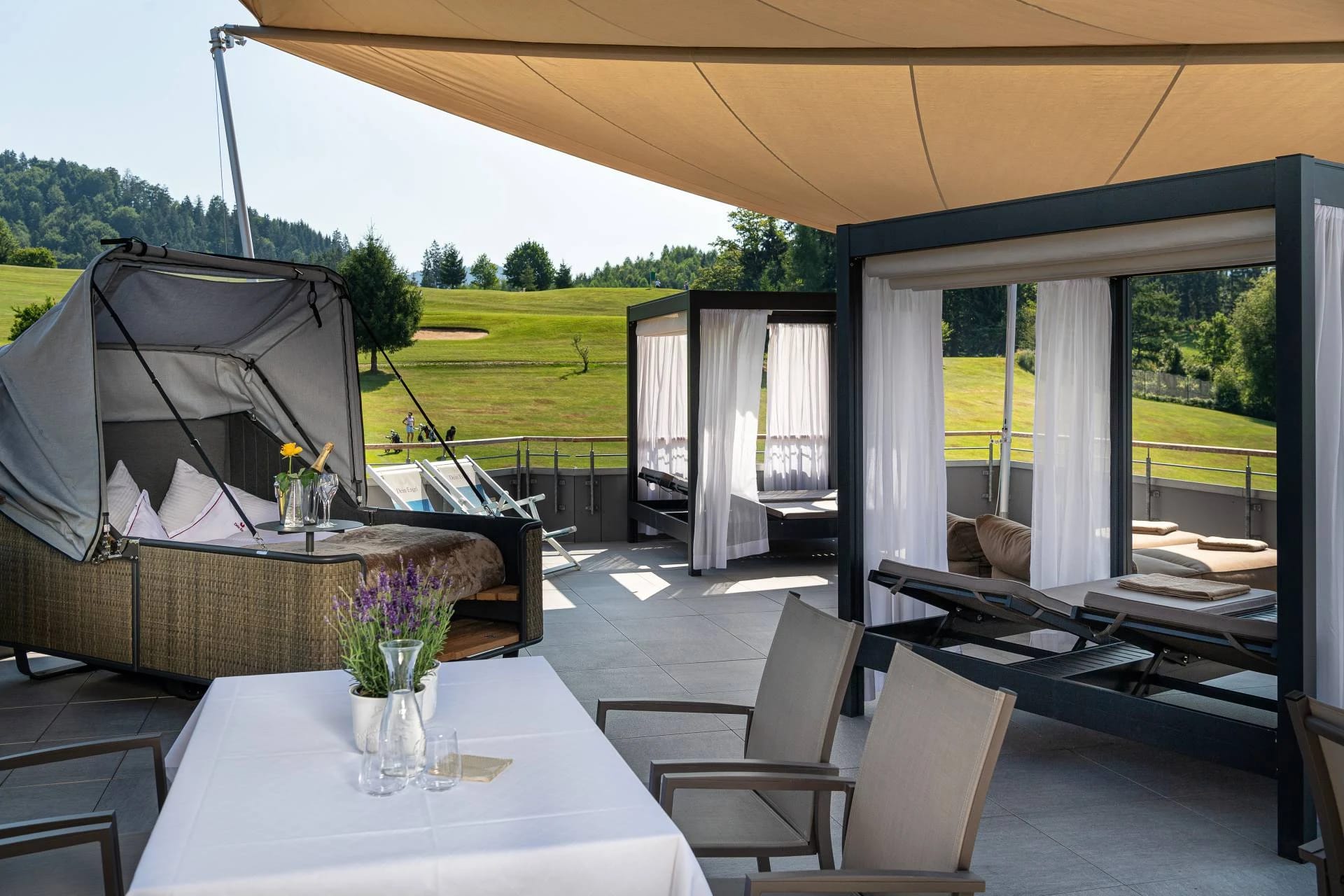 Dachterrasse mit überdachten Doppelliegen und Blick auf Wiesen und Golfplatz