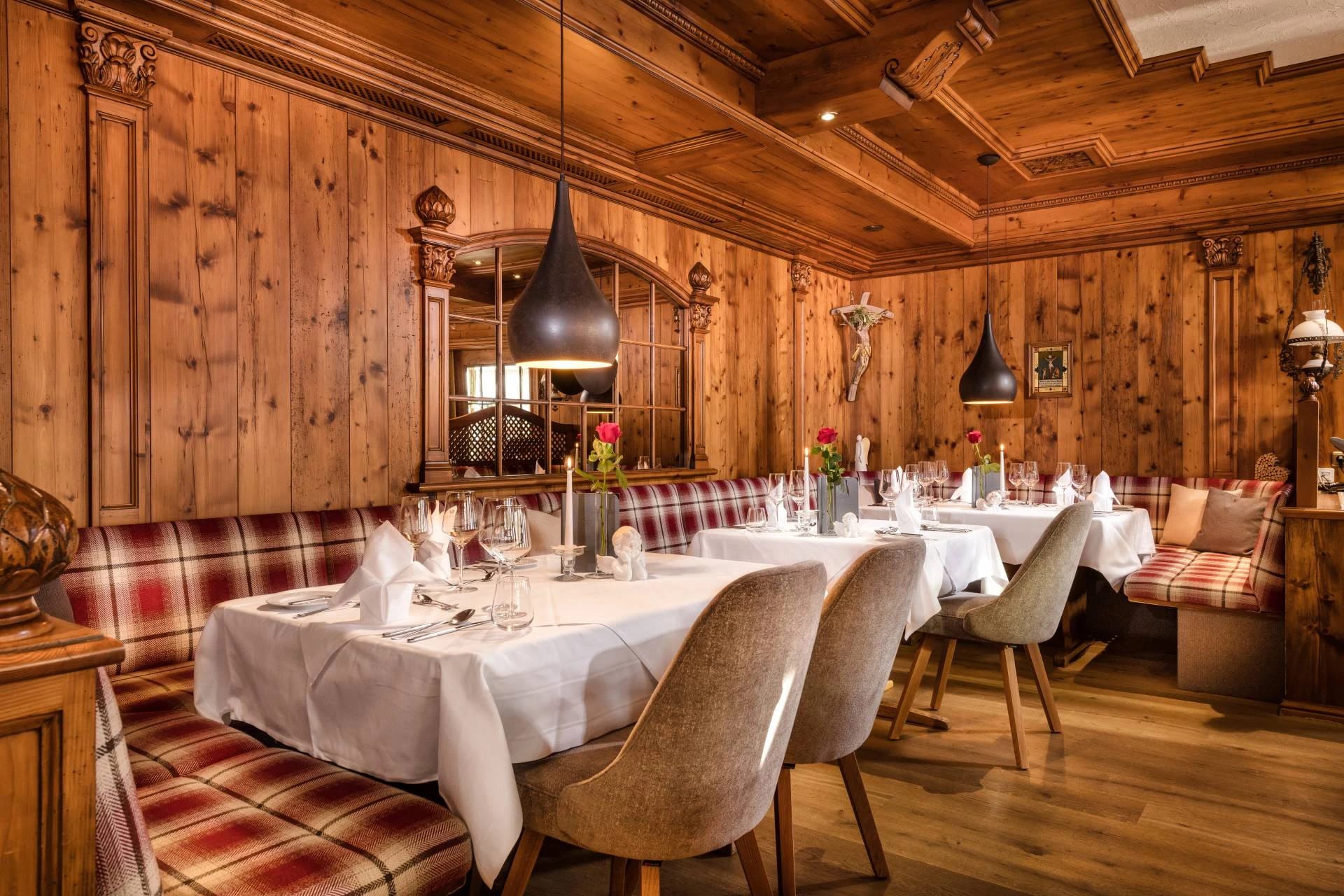 Holzvertäfelte Gaststube mit eingedeckten Tischen und karierten Sitzbänken