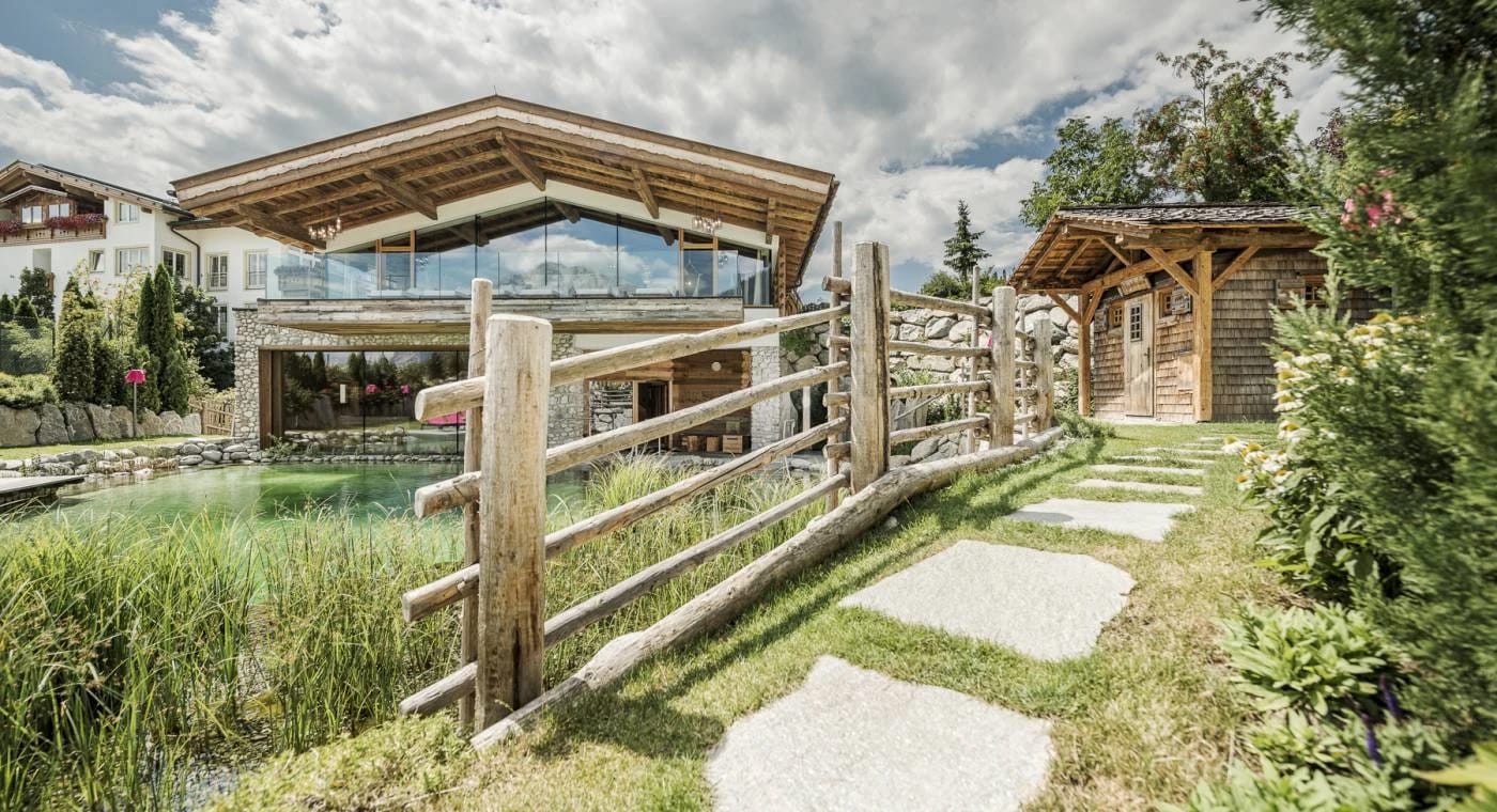 Gartensauna aus Holz an einem Naturteich mit Steinweg