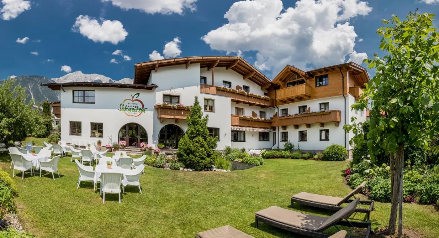 Außenansicht des Biohotel Schweitzer mit Gartenwiese und Liegestühlen
