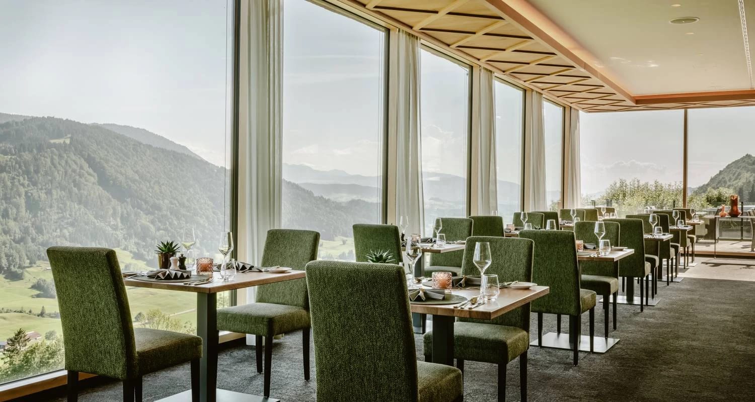 Restaurant mit grünen Stühlen und Panoramafenstern zum Bergblick