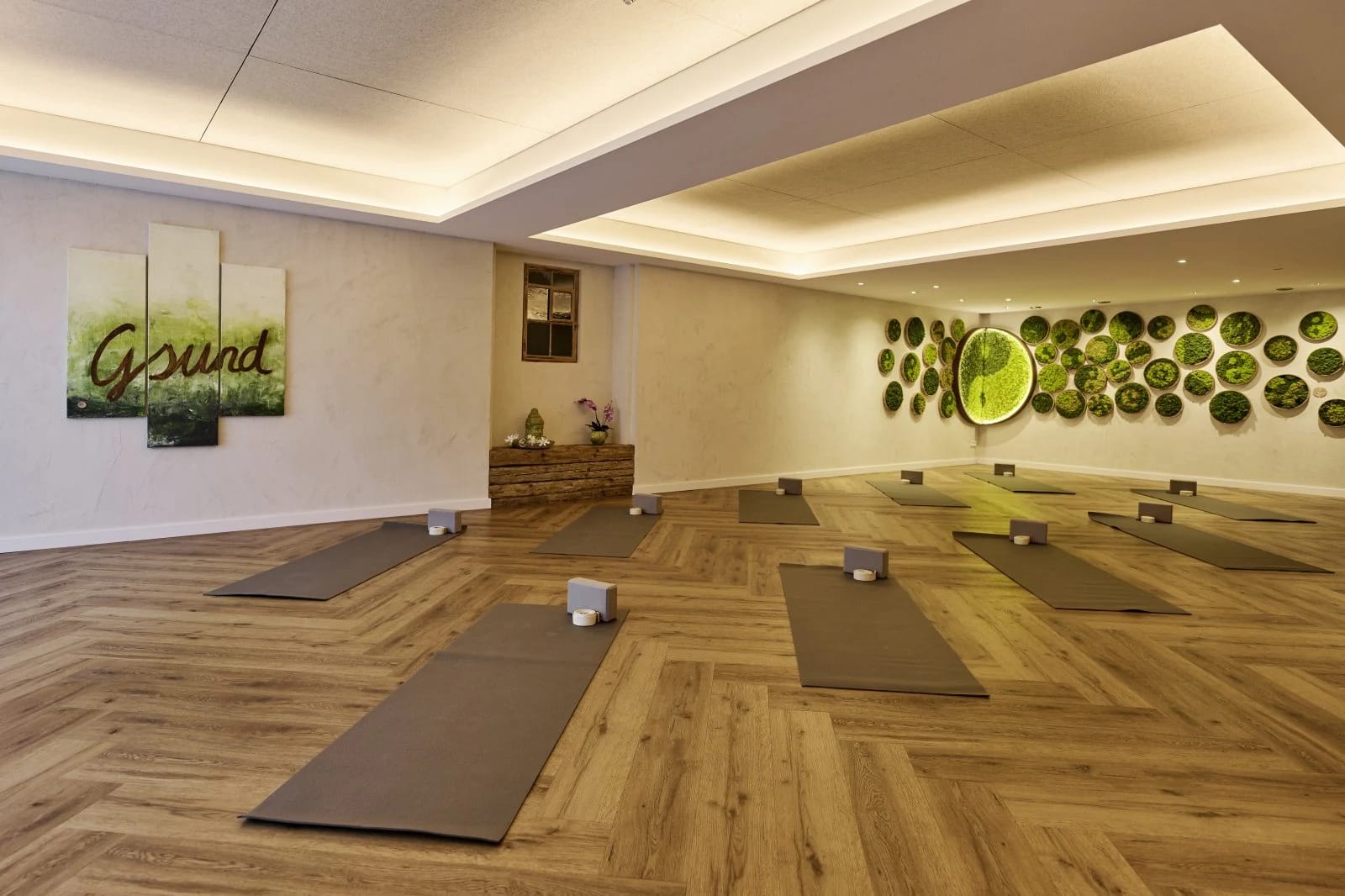 Gymnastik- und Yogaraum mit ausgelegten Matten und grüner Wandgestaltung