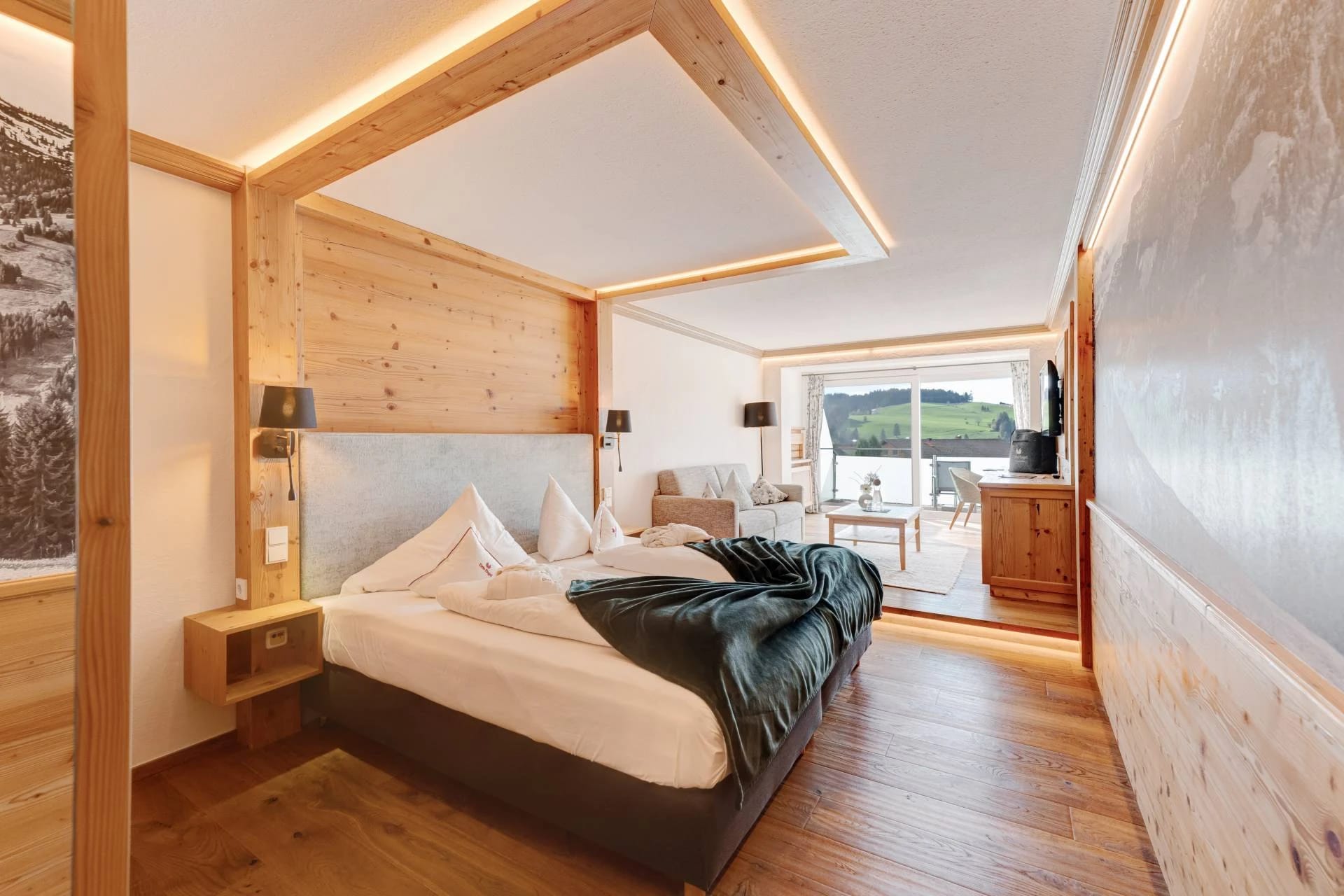 Modernes Doppelzimmer mit beleuchteter Holzwand hinter dem Bett und Zugang zum Balkon