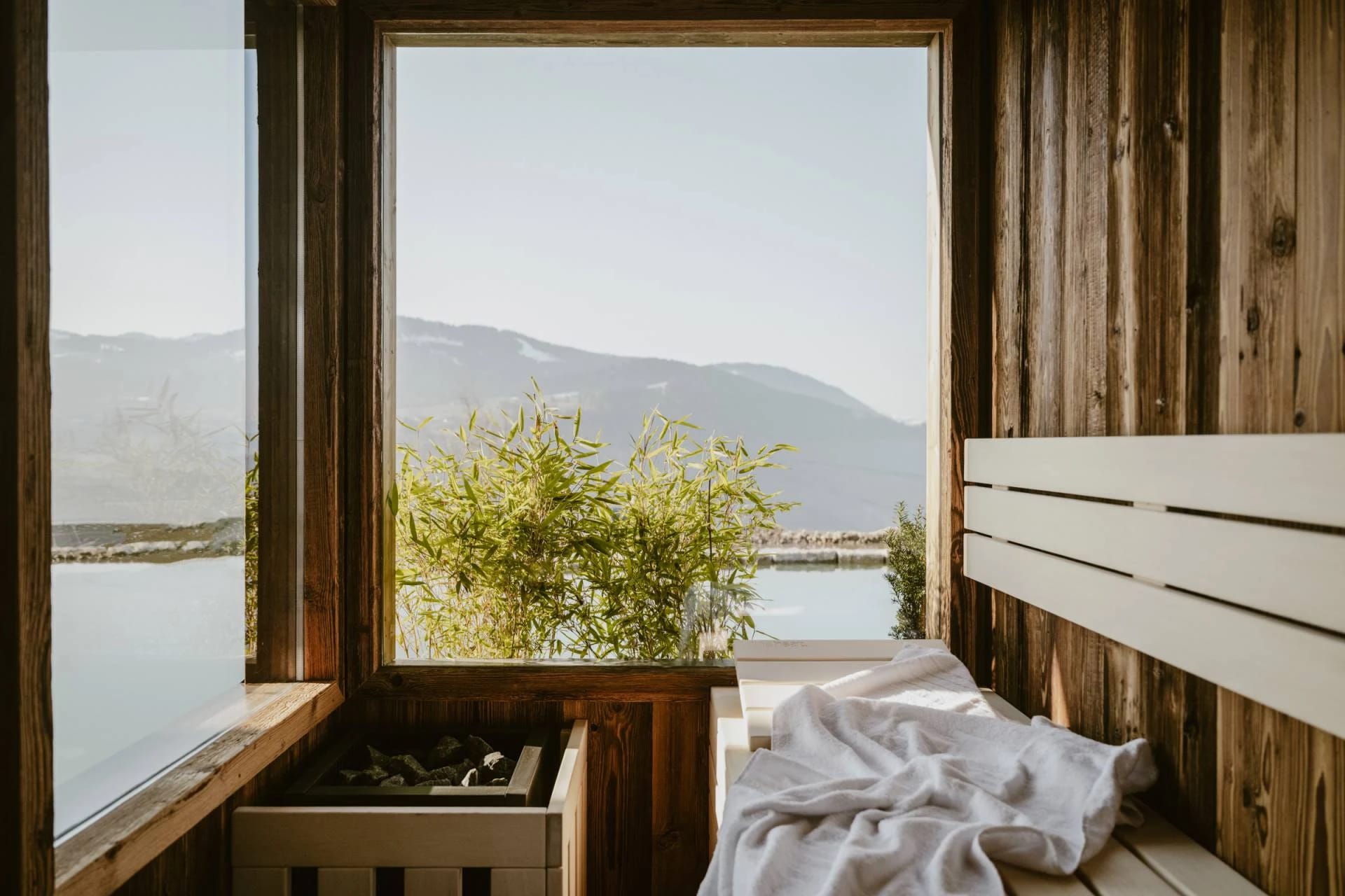 Sauna aus Holz mit großem Panoramafenster und Blick auf die Berge