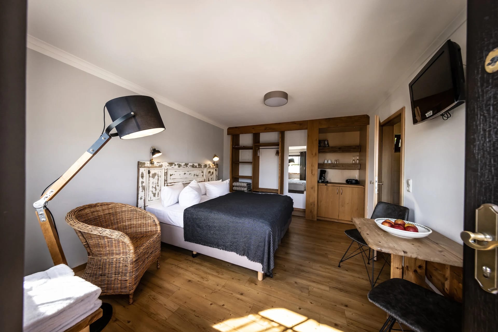 Doppelzimmer mit Doppelbett, Korbsessel, Stehlampe und Holzboden