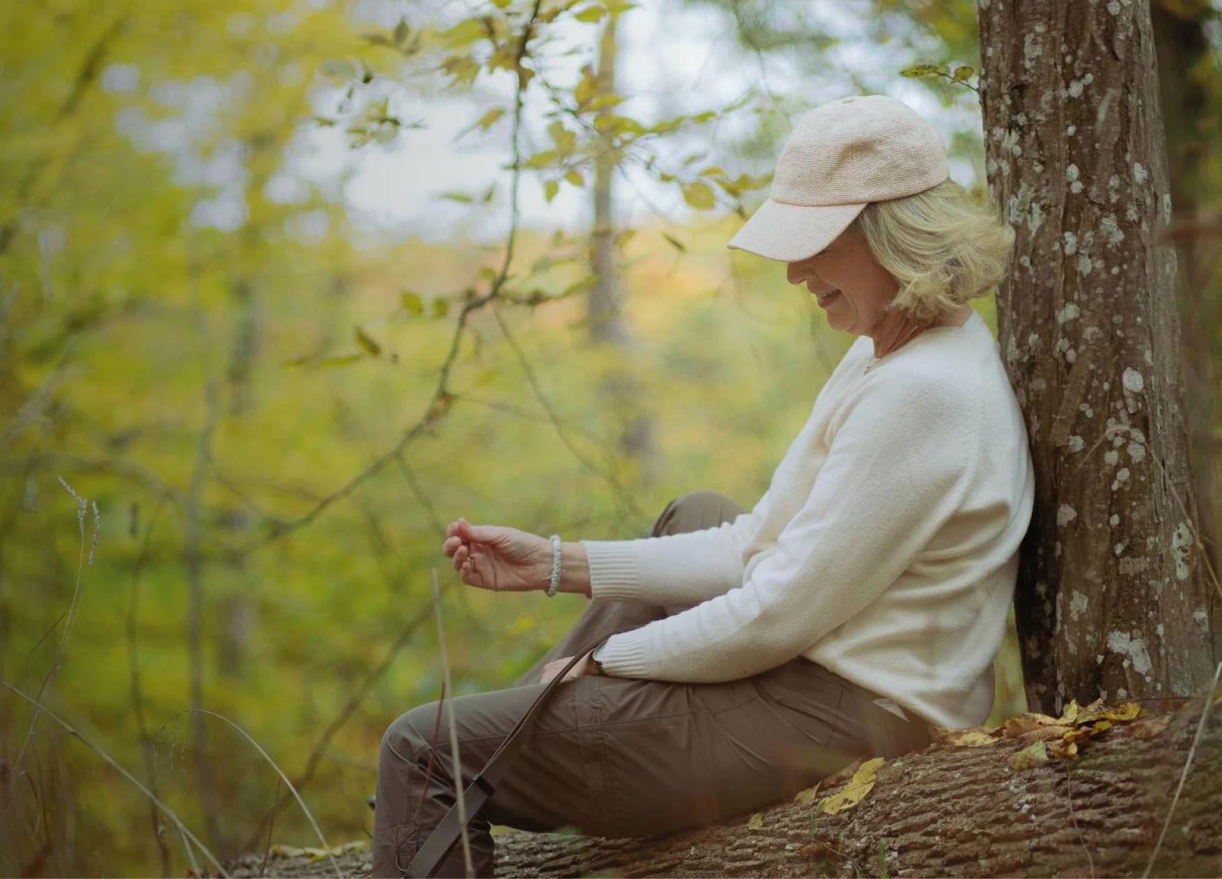 Kerstin Rogowski sitzt im Wald an einen Baumstamm gelehnt