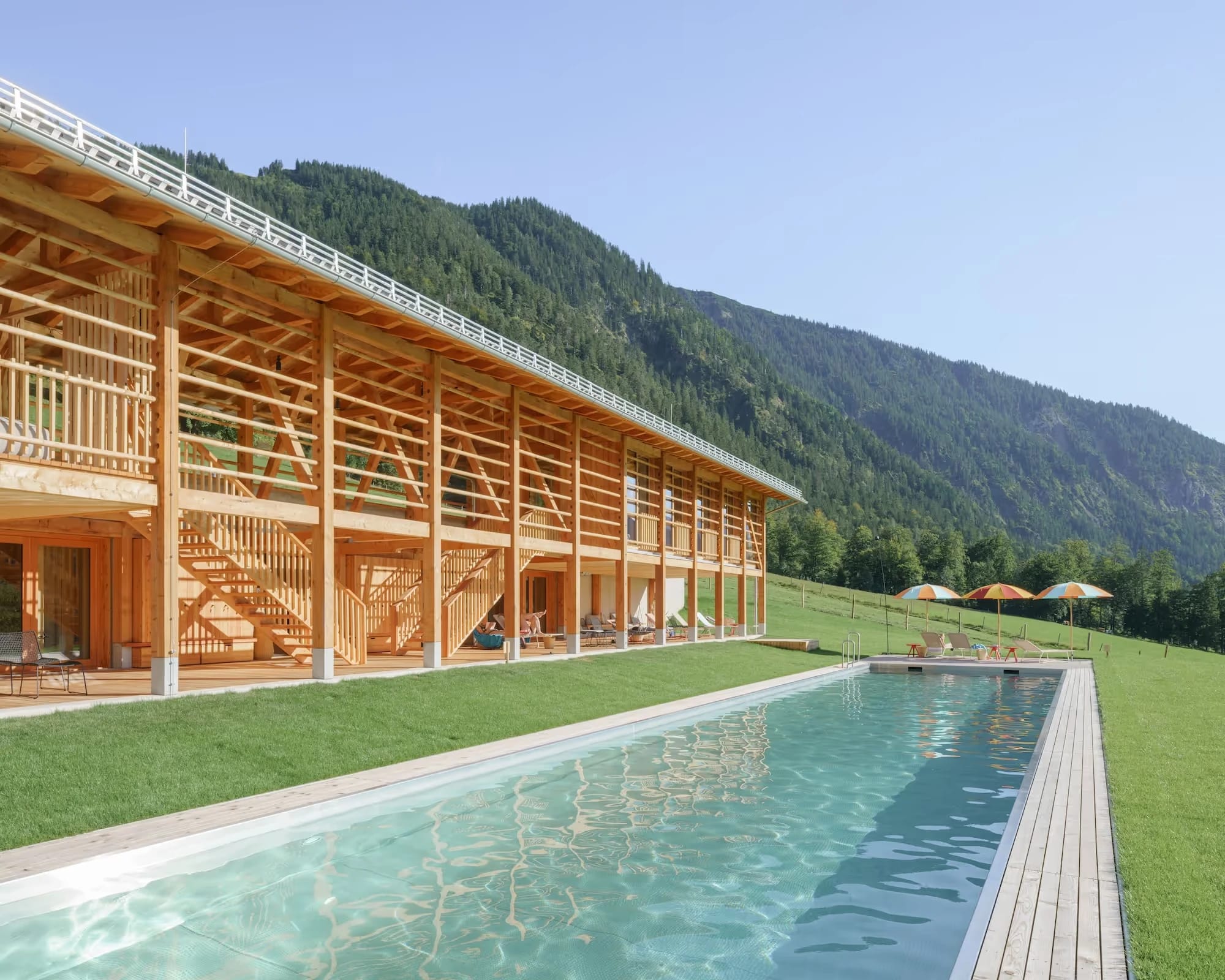 Badeharpfe des Tannerhof mit Außenpool, Liegestühlen und Bergpanorama unter blauem Himmel