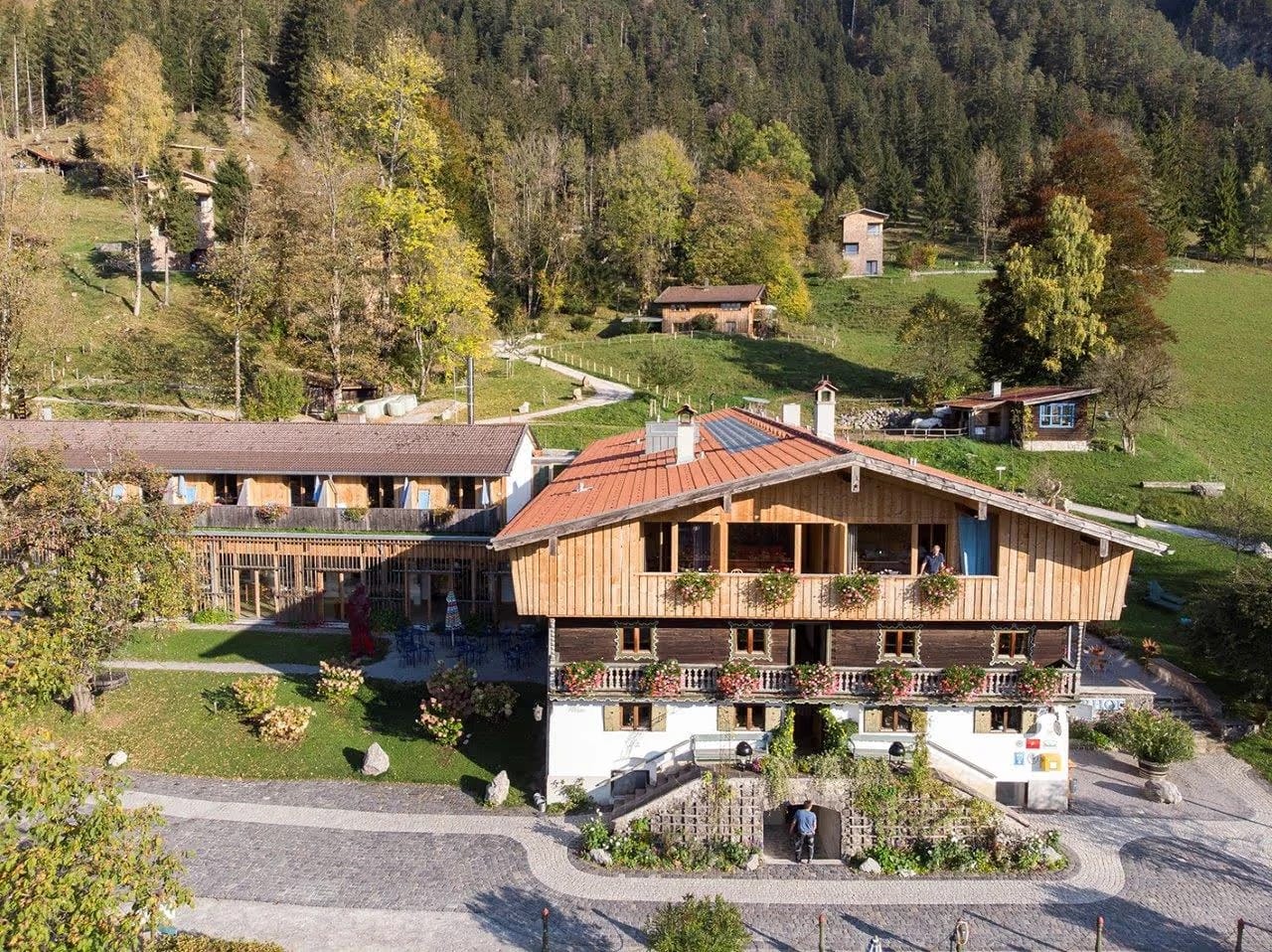 Luftaufnahme des Tannerhof Bayrischzell im Herbst mit Hauptgebäude, Nebengebäuden und Alpenpanorama