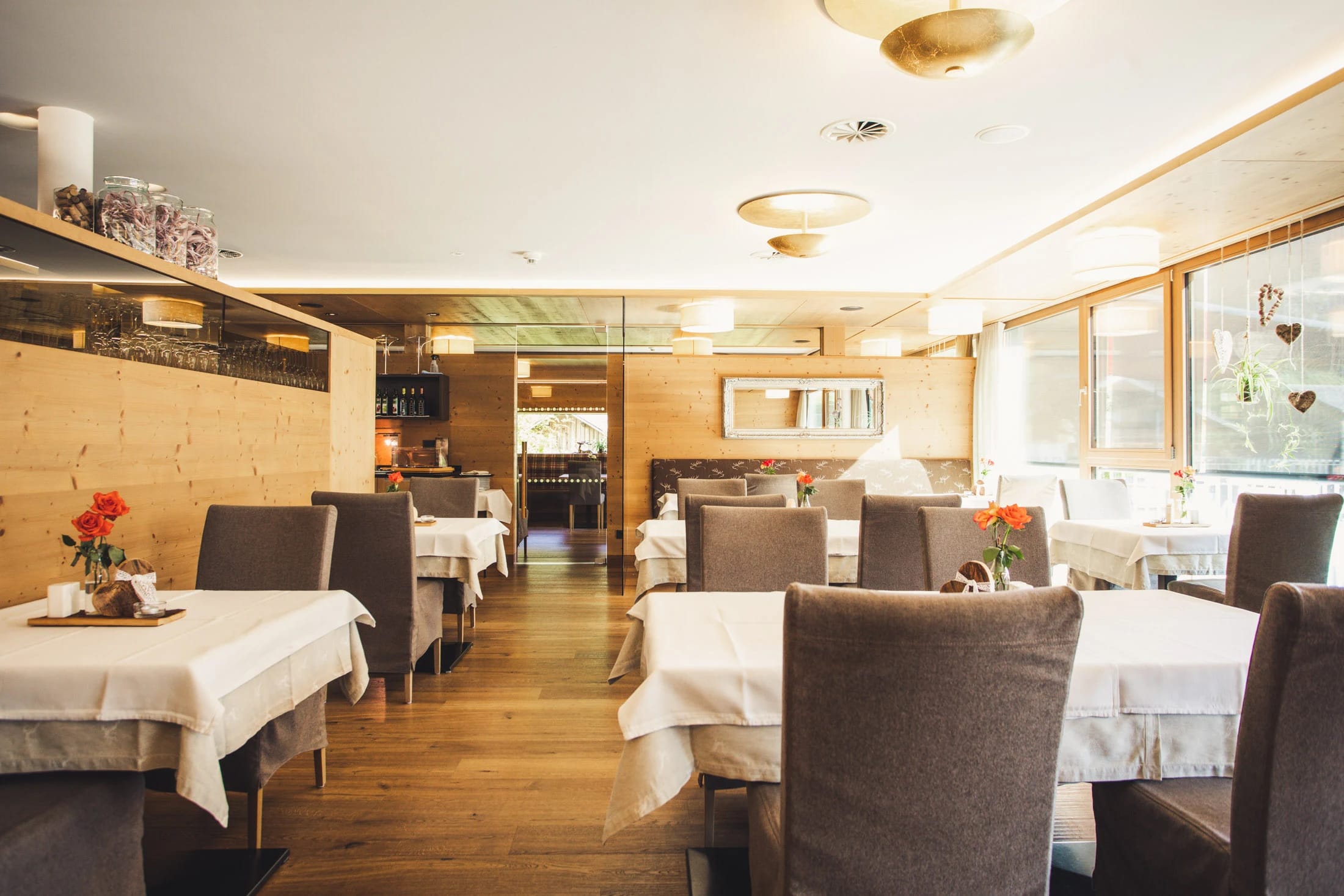 Restaurantstube mit eingedeckten Tischen, Holzvertäfelung und warmer Beleuchtung