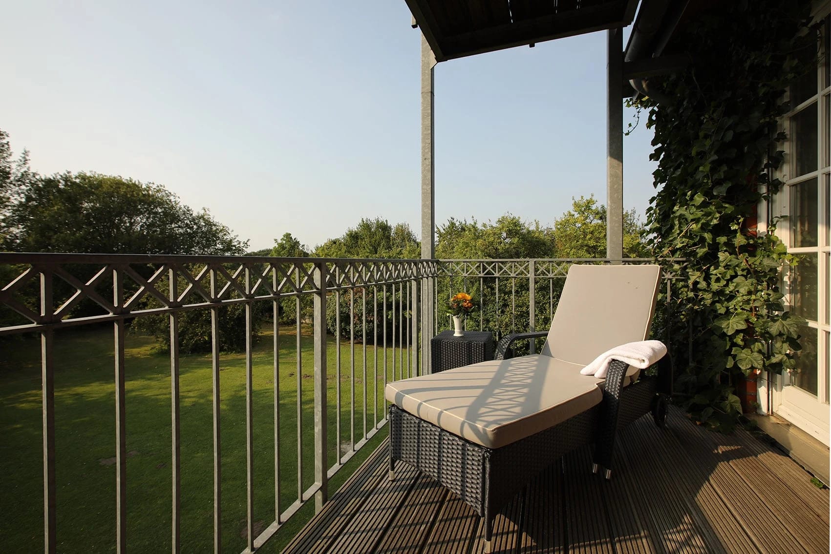 Zimmerbalkon mit Liege und Blick in den Garten