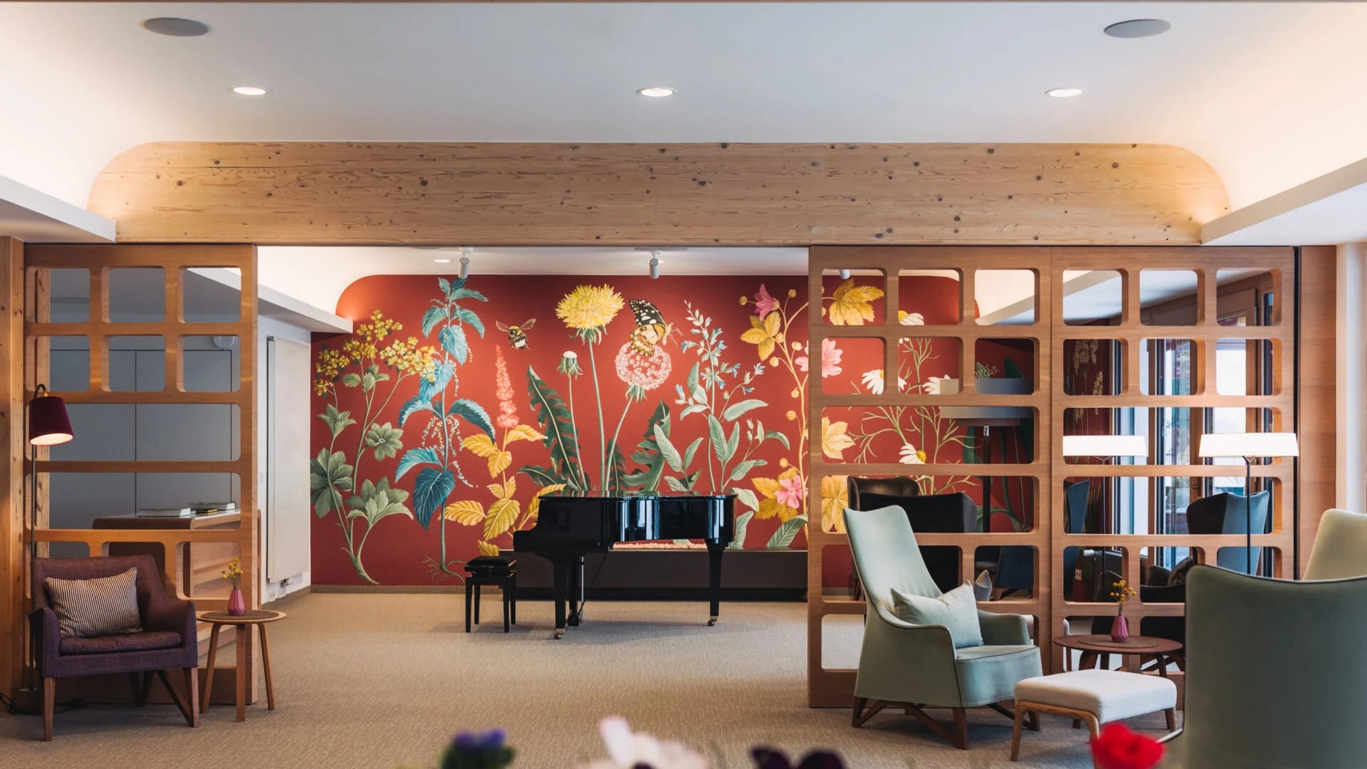 Lobby mit Flügel vor rotem Blumenwandbild, Sesseln und Bücherregalen
