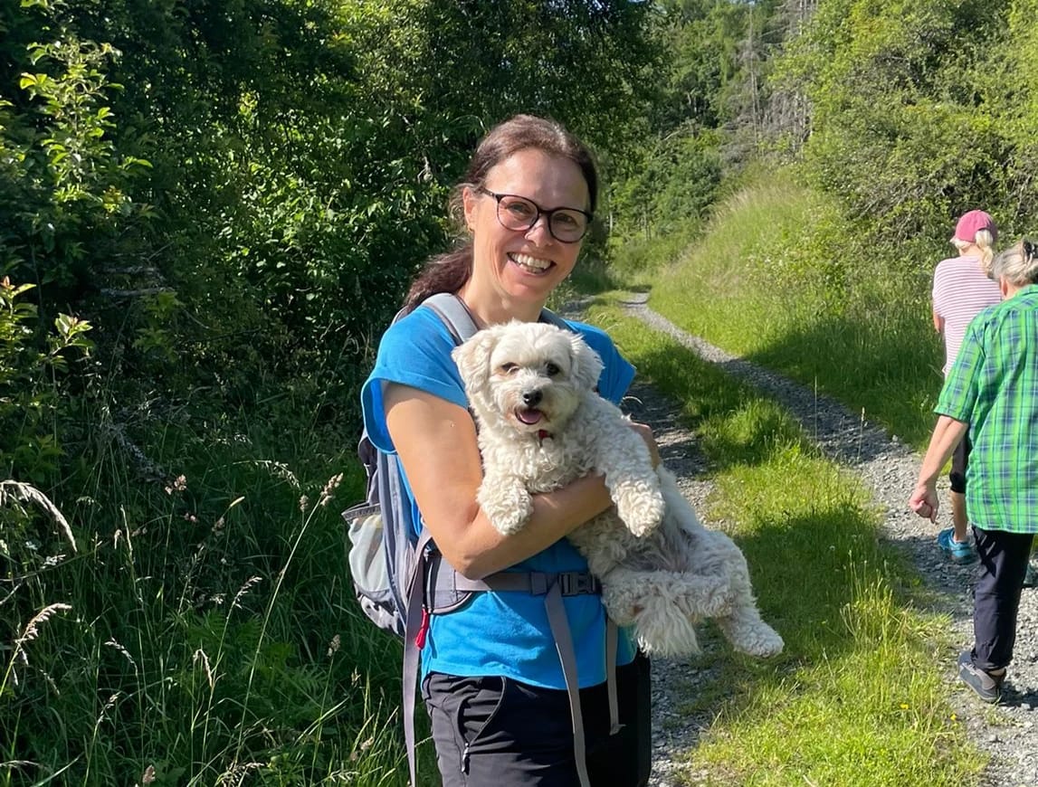 Sabine Czilwa auf einem sonnigen Wanderweg, im Hintergrund weitere Wandernde