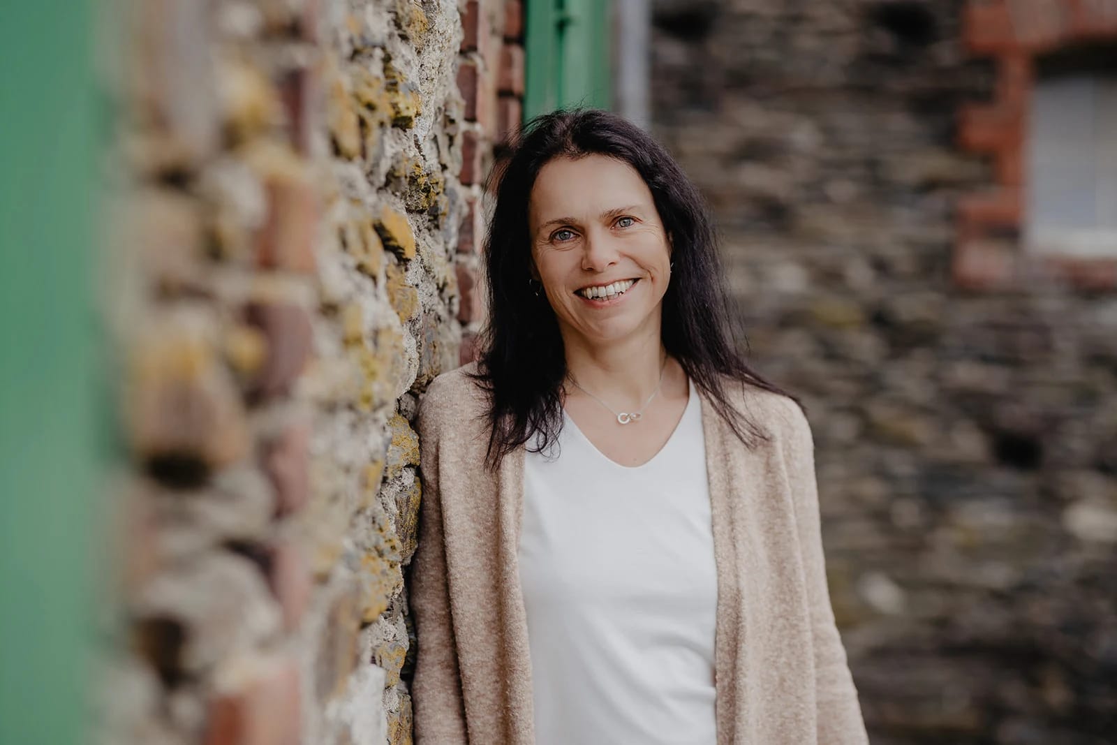 Porträt von Sabine Czilwa vor einer Natursteinmauer