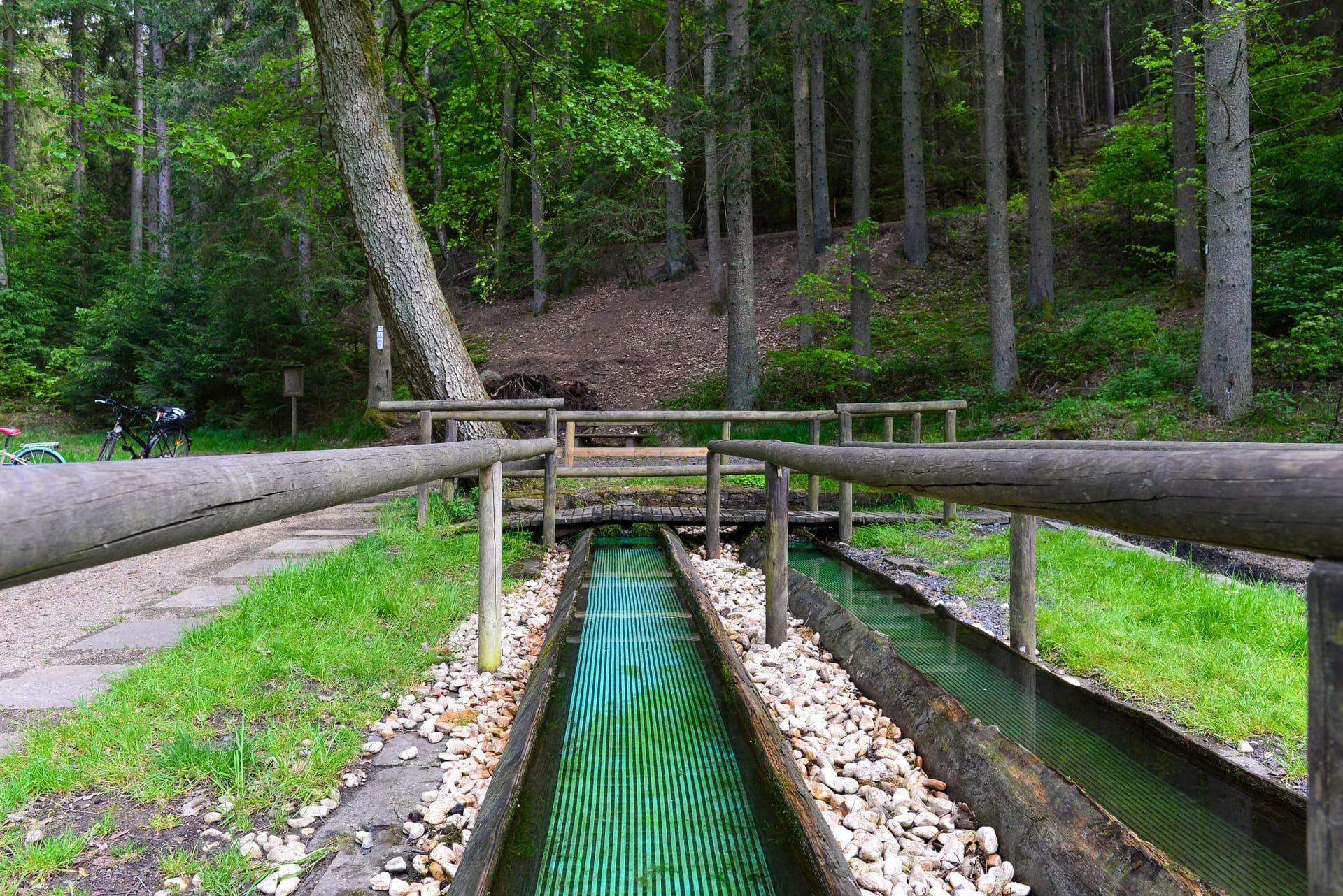 Kneipp-Tretbecken im Wald mit Holzgeländer und Kieselsteinen