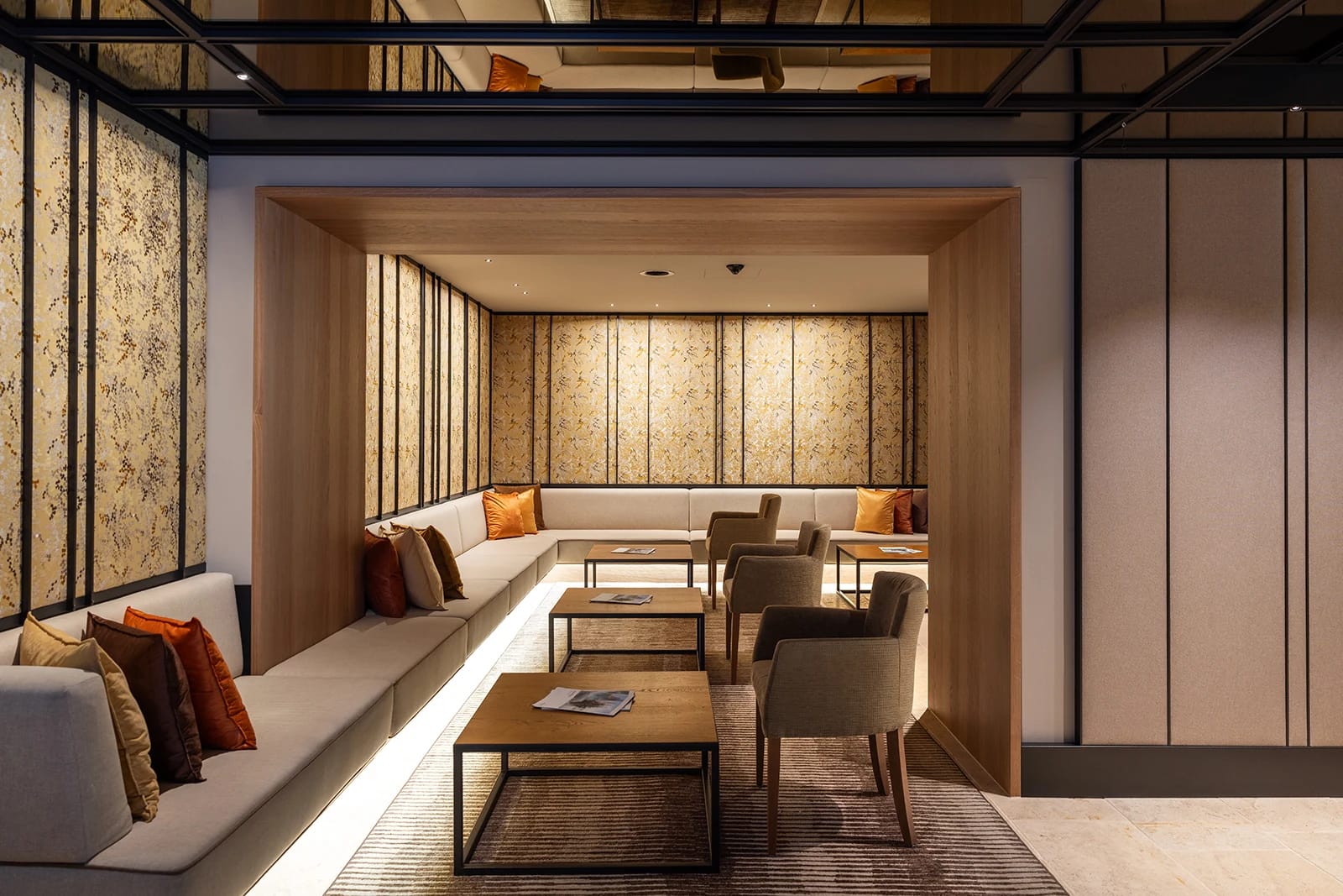 Lounge mit langer Sitzbank, Kissen, Sesseln und Beistelltischen