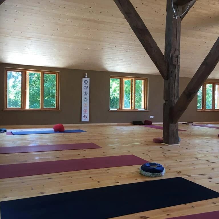 Heller Seminarraum mit Holzdielen, sichtbaren Dachbalken und ausgelegten Yogamatten