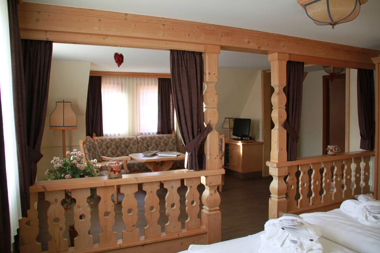 Appartement mit hölzerner Balustrade, Sitzecke mit Sofa und angrenzendem Schlafbereich