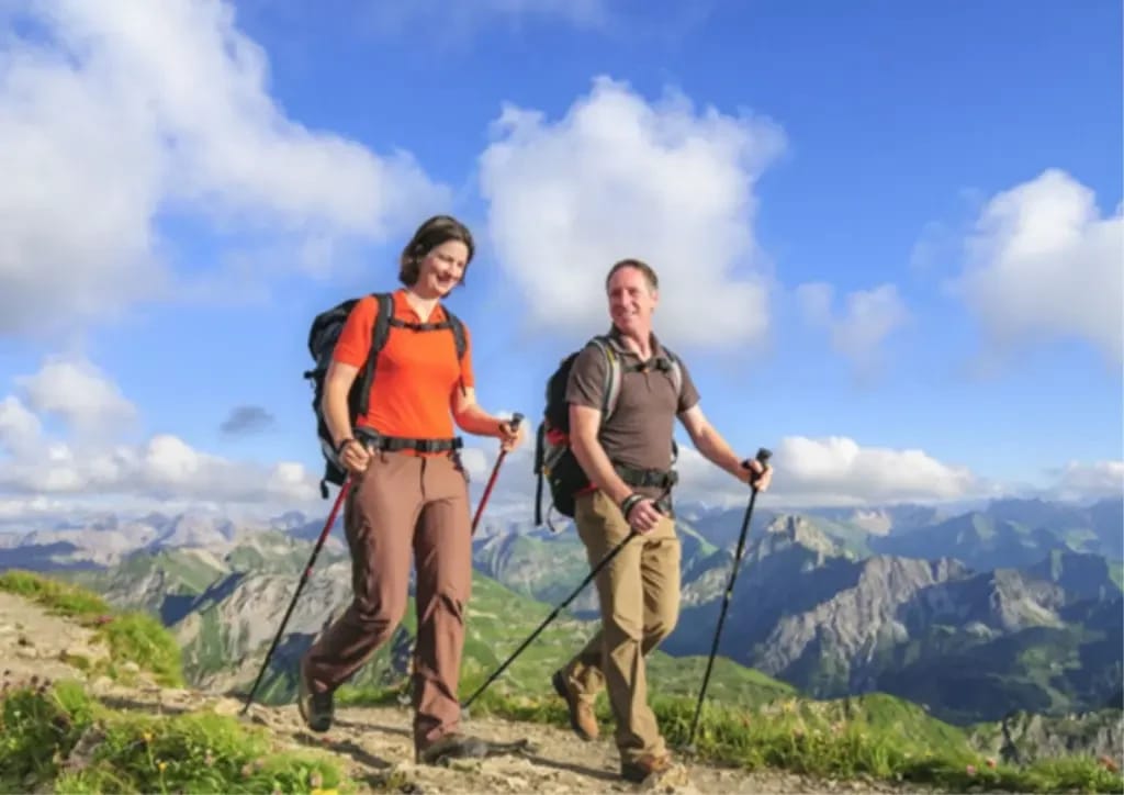 Zwei Wanderer auf einem Bergkamm mit Alpenpanorama