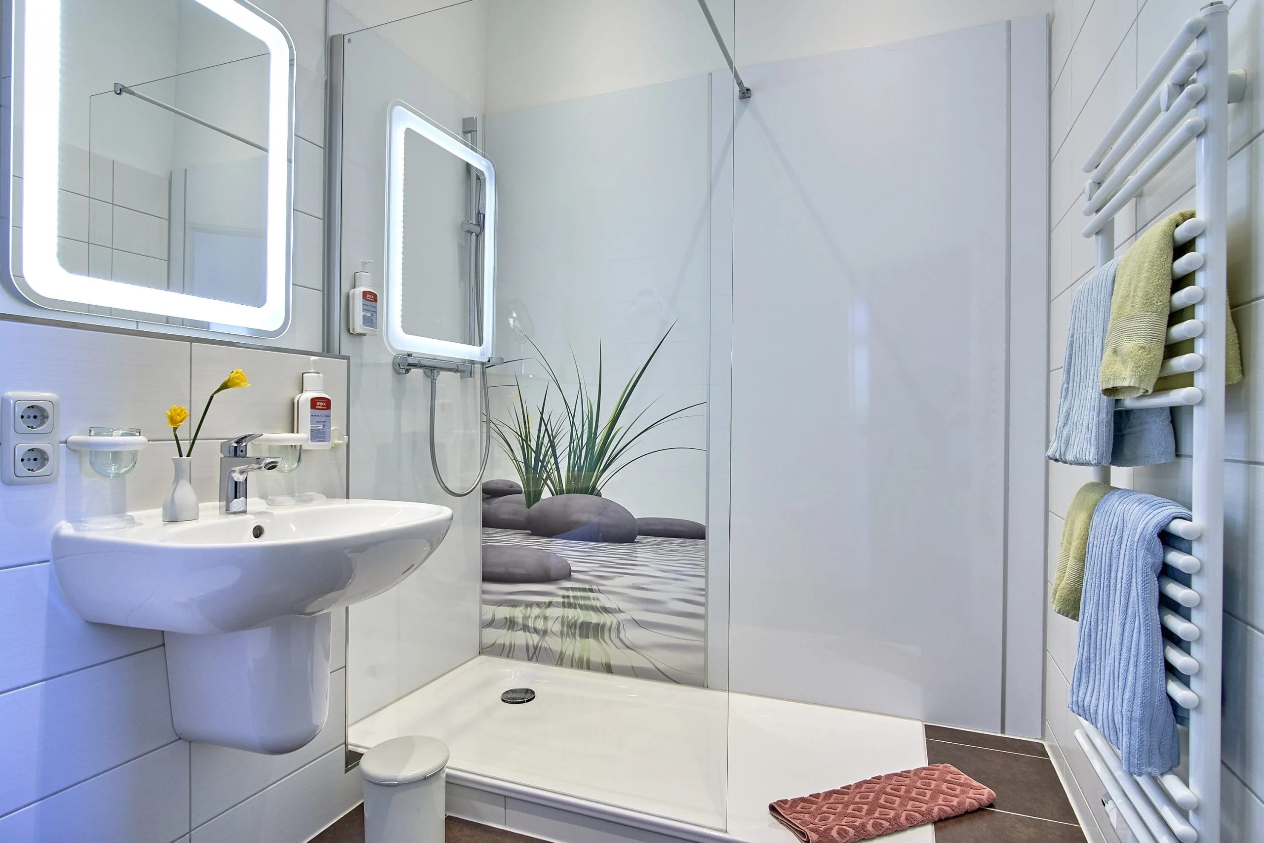 Modernes Bad mit bodengleicher Dusche, Waschbecken und beleuchtetem Spiegel