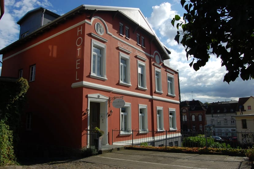 Rotes Hotelgebäude mit weißen Fensterrahmen und senkrechtem HOTEL-Schriftzug unter blauem Himmel