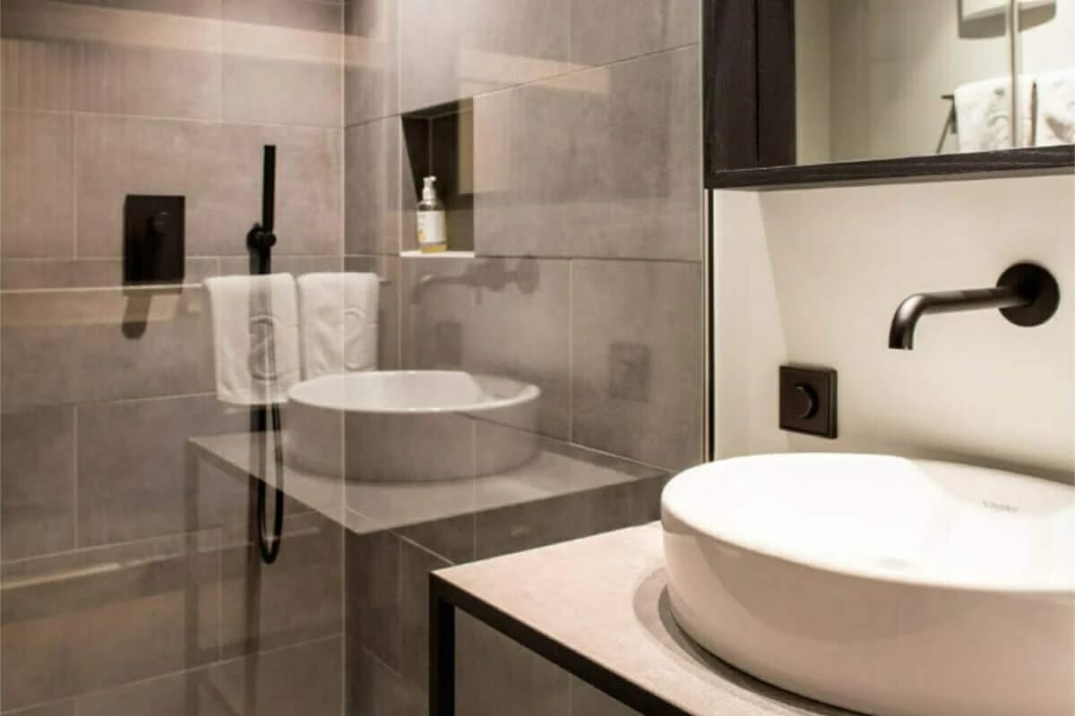 Badezimmer mit bodengleicher Glasdusche und zwei runden Aufsatzwaschbecken