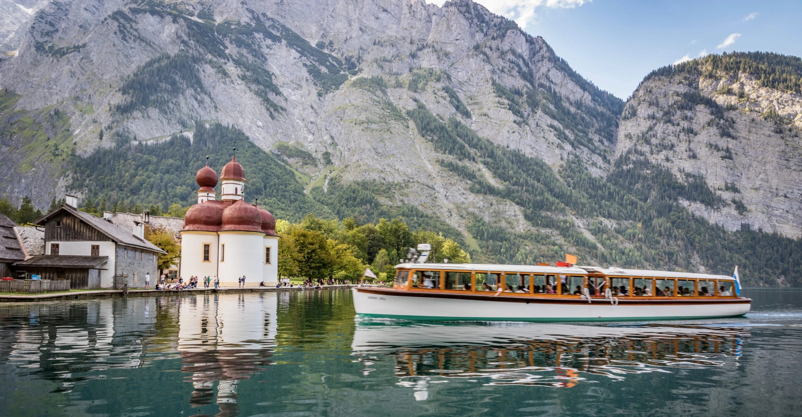 Ausflugsschiff auf dem Königssee vor der Wallfahrtskirche St. Bartholomä und den Berchtesgadener Alpen