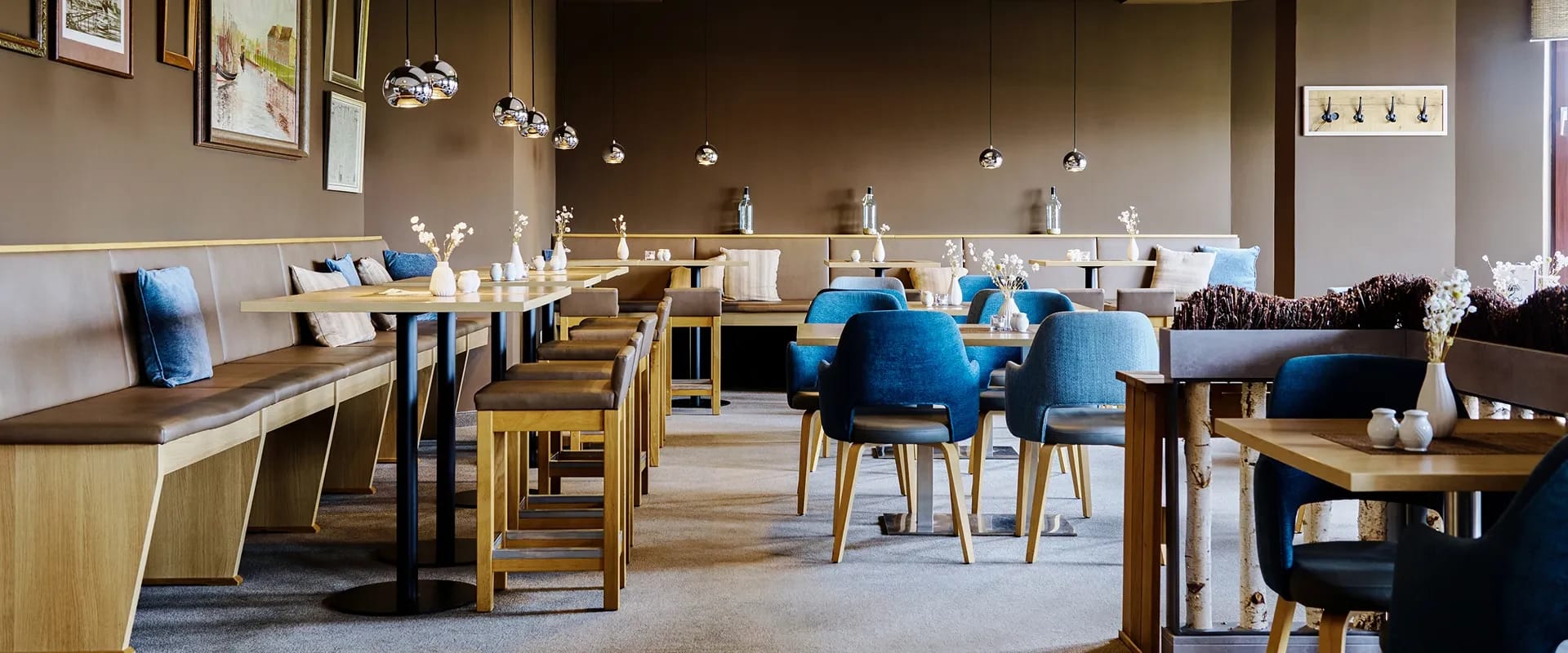 Restaurant Brasserie tween mit gedeckten Holztischen und blauen Stühlen